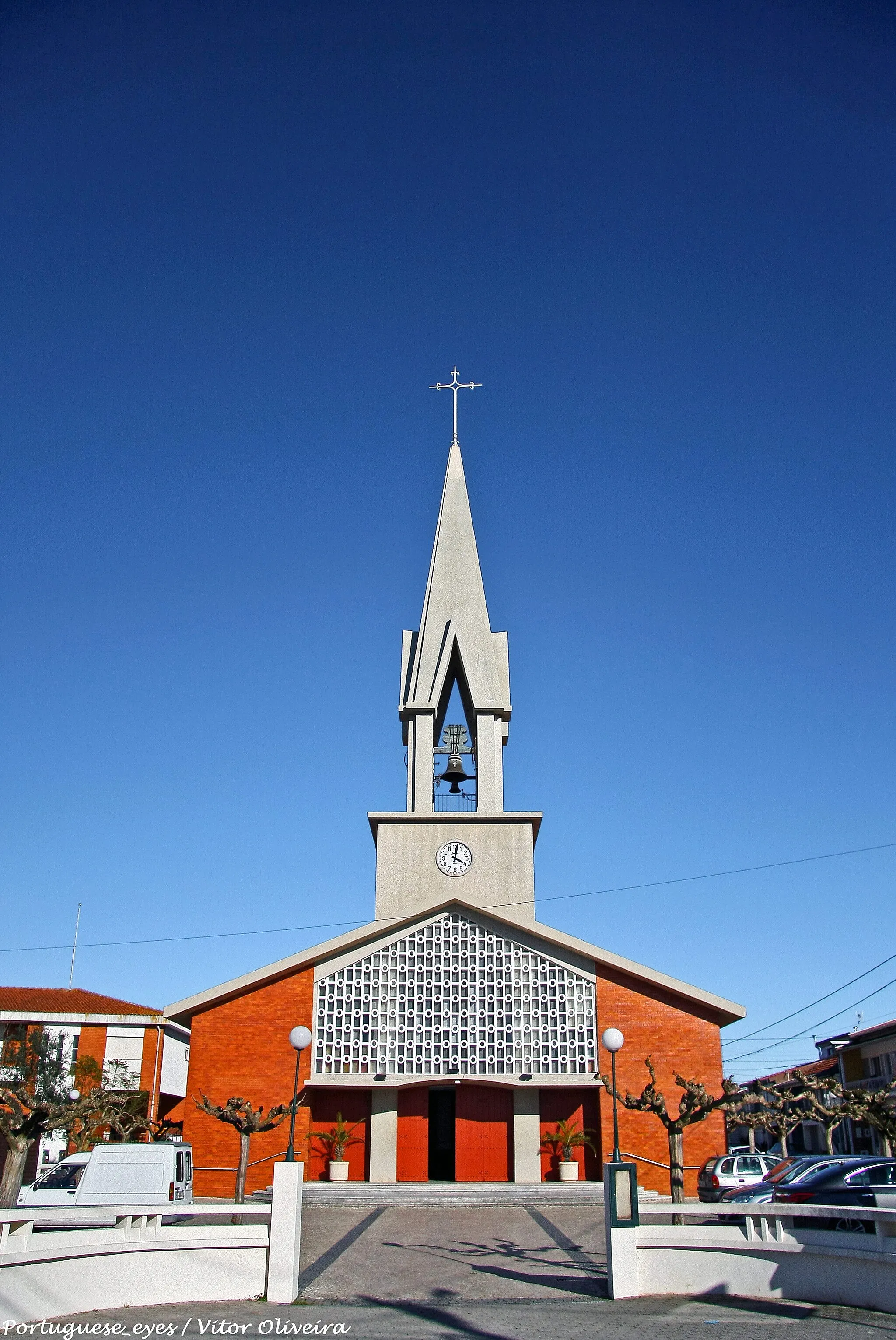 Photo showing: A Igreja de S. Pedro é um templo de características modernas.
A sua construção foi iniciada em 18 de Agosto de 1957, com a bênção da primeira pedra na presença do Bispo de Aveiro, D. Domingos da Apresentação Fernandes.
Foi sagrada em 15 de Agosto de 1964, pelo Bispo de Aveiro D. Manuel de Almeida Trindade.
Foi Pároco durante a sua construção, o Padre Manuel Oliveira.
Possui ao centro, na capela-mor, um Cristo Crucificado de grandes dimensões, ladeado por duas imagens. A de S. Pedro, patrono da freguesia, e a de Nossa Senhora, imagens são recentes e de madeira.
Tem uma pintura de 1966, representando o baptismo de Cristo, assinada por Molina Sanchez.
Em 2006 o Conselho Económico promoveu obras de conservação neste templo, dotando-o de melhores condições para a liturgia eucarística e baptismal que ali se celebra.
A nave principal sofreu algumas adaptações tendo, em recantos, dando a ideia de capelas laterais, a capela do Santíssimo, com o Sacrário e o Baptistério, com a Pia Baptismal e uma pintura de grandes dimensões representando o baptismo de Cristo, da autoria de Molina Sanchez.
- Centro Paroquial e Residência Paroquial - Aspectos históricos
“A necessidade de tão vultuoso empreendimento (que reúne a Igreja Nova, a Residência e o Centro Paroquial), justificava-se pelas reduzidas dimensões da Velha Igreja de Vila Nova e pelo deficientíssimo estado de conservação em que se encontrava a, também, velho casa, que servia de residência paroquial.
Deste modo, lançada a ideia e dada a extraordinária adesão de todos os palhacenses, passou-se à concretização da mesma. Estava em marcha o maior empreendimento, já levado a cabo na Palhaça e que viria a custar à freguesia cerca de três mil contos.”
– Horácio Pires, in «Freguesia da Palhaça, Contribuição para a sua Monografia», Publicação do Centro Paroquial da Palhaça, 1977.
O projecto inicial incluía a construção da Nova Igreja, da Residência Paroquial e ainda de um salão, destinado ao serviço paroquial.
Em terreno oferecido por Padre José Belinquete foi possível construir o Centro Paroquial.
O Padre Mário Bacalhau elaborou o esboço que serviria de base ao projecto e a obra inicia-se no ano de 1968. A empreitada da primeira fase da construção foi adjudicada a Manuel Lourenço Carvalho. O Sr. Luís Apolónio encarregou-se dos acabamentos, tendo sido inaugurado a 12 de Setembro de 1971. O Centro Paroquial acolheria actividades de catequese, reuniões de grupos, de pais e outras. Até Dezembro de 1975 foi também espaço da Telescola na Palhaça.
A 1 de Junho de 1978, começou ali a funcionar uma Creche. Actualmente é sede do Jardim-de-infância do Centro Social Paroquial.

Em 2007 foi arranjado o espaço existente em frente ao Centro de Dia, para uso dos utentes. Este espaço foi chamado de Jardim Padre José Martins Belinquete, por ter sido doado por este sacerdote. www.paroquia-palhaca.pt/node/5