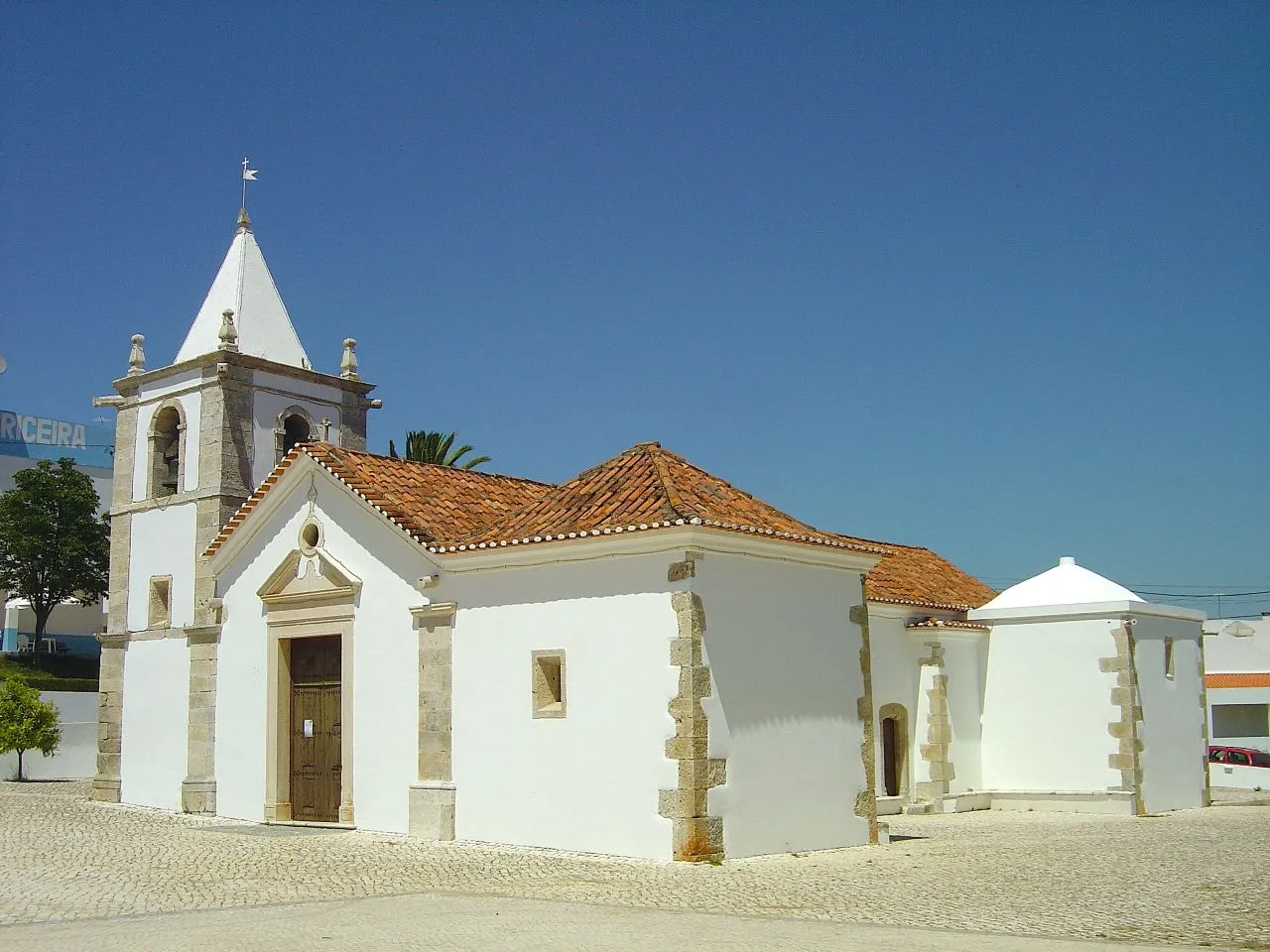 Photo showing: Construída em 1511, a Igreja Matriz da Louriceira é, de todo o seu património, o edifício com maior interesse histórico e arquitectónico. De invocação a Nossa Senhora da Conceição, este templo tem sofrido várias alterações, das quais se salientam as reconstruções de 1560 e de 1942, tendo sido recentemente classificado como imóvel de interesse público. Esta igreja, de estilo manuelino, posteriormente alterado, tem empena de bico ladeado por uma torre baixa de base quadrangular de feição quinhentista, as portas laterais são manuelinas, com as vergas golpeadas; no extra-dorso da capela-mor existem três gárgulas ornamentais. O corpo do templo é revestido por azulejos azuis e brancos do século XVI, que anteriormente o deviam revestir totalmente. No pavimento da capela-mor há uma lápide sepulcral digna de referência com um leão no escudo e no epitáfio semi-apagado, em que se diz serem os jacentes Lopo Dias Fayn, fidalgo da Casa d’El Rei falecido em 20 de Janeiro de 1560 e sua mulher.
No fecho da cúpula da torre pode ver-se a data de 1561.
A torre tem um sino documentado: BELLAS – R. DOS MASTROS – LISBOA. Da estatuária da igreja merece destaque uma imagem de Santa Luzia, um nicho do altar mor em pedra do século XVI, posteriormente pintado, um S. Vicente em pedra do século XVI, uma Nossa Senhora em pedra do início do século XVII e uma imagem de S. Sebastião, boa escultura de pedra do século XVI. www.cm-alcanena.pt/pt/conteudos/concelho/Patrim%c3%b3nio/...

See where this picture was taken. [?]