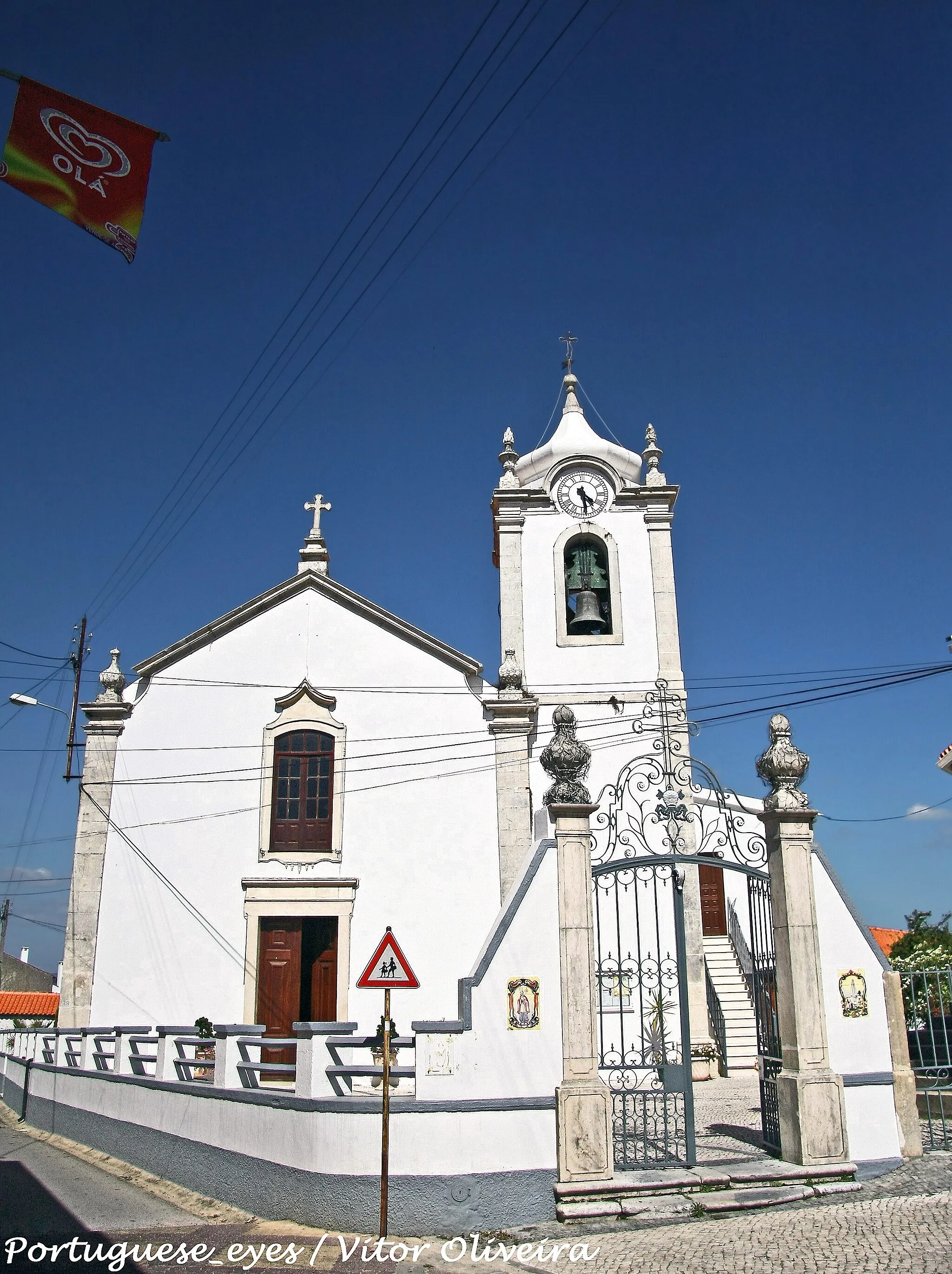 Photo showing: Ignora-se a data da sua construção, sabendo-se contudo que é muito antiga, parecendo ser muito mais moderna a torre da Igreja.
Vemos dificuldades em investigar os factos onde não chega a memória dos homens e que a história geral não regista.
Em 1861, a Junta de Paróchia mandou proceder à demolição e reconstrução de toda a parede do lado norte, por esta se encontrar em deplorável estado, havendo o risco de desabar. Durante as obras, foi colocada uma cortina do lado norte, tendo-se celebrado os actos religiosos.
Em 1873, fez-se novo madeiramento e telhado, estucou-se o tecto e solhou-se o corpo principal da Igreja e da sacristia, pois o tecto de madeira estava a cair, o madeiramento e telhado encontravam-se em péssimo estado.
Em 1875 foi colocado o actual portão de ferro, que fecha o adro, substituindo uma porta de madeira. Assim, poderá concluir-se que a Igreja naquela época já seria muito antiga.
Antes da existência da porta de madeira, havia um muro muito baixo com uma abertura que servia de entrada. Junto a esta entrada, existia um fosso com cerca de 1,00m de profundidade por 1,50m de largura, para impedir a entrada de cães, porcos e outros animais para o adro. O fosso era atravessado por barrotes que serviam de passadiço. Posteriormente aterrou-se e colocou-se na abertura do muro, um cunhal de cantaria com uma porta de madeira, alteando-se os muros por essa ocasião.
Em 28 de Abril de 1882, foi colocado na ventana da torre do lado sul, um sino que fora refundido por se encontrar quebrado havia muitos anos, que as pessoas mais velhas da freguesia, não se lembravam de o ver em bom estado.
Provavelmente, em época longínqua, por piedade dos primeiros habitantes, ou generosidade do senhor do prazo (Quinta de S. Silvestre), se edificou uma ermida, que até ser o edifício que é, quantas modificações se terão efectuado.
Desde a fundação da Igreja, o Padroado e a Quinta, andaram intimamente ligados, pelo que será provável que alguém dos antigos possuidores do prazo, edificasse a Igreja ou pelo menos desse o terreno para nele se construir o edifício, facto este só por si, poderia originar o direito de padroado. Também se pode supor, que as primeiras cerimónias religiosas, que nestes sítios se celebravam, tivessem lugar nalguma pequena ermida, que por acrescentamentos e reconstruções sucessivas, se transformasse na igreja que hoje existe.
D. Fernando, doou ao seu alferes-mor Ayres Gomes da Silva, o prazo e padroado, que por infidelidade deste à coroa, D. João 1º lhe sequestrou todos os bens, doando parte deles, incluindo a Quinta de S. Silvestre a um dos seus filhos João Gomes da Silva.
No ano de 1441, João Gomes da Silva, recebe o padroado e o prazo, por doação de D. João I, com testamento feito em S. Marcos, sucedendo-lhe seu filho Ayres Gomes da Silva em 1444.
Em 1721, o prazo de S. Silvestre, foi comprado por Manuel Castanheda Cabral e Horta, fidalgo cavaleiro com brasão de armas (Sargento-Mór de Coimbra e oitavo neto de D. Armando Barreto - Senhor do Baião).
De 1746 a 1767, foi Prior de S. Silvestre, José da Veiga Cabral de Moura Rangel.
Sabe-se que em 1783, o Prior Manoel Antunes Ferreira começou a paroquiar esta freguesia.
De 1805 a 1831, foi prior José de Nápoles Pereira Coutinho de Vilhena, fidalgo cavaleiro com brasão de armas. Nasceu e faleceu em S. Silvestre.
Em 1824, o padroado passou para a coroa por decretos.
O último padroeiro foi Manuel Cabral de Moura Coutinho de Vilhena.
A Igreja que se situa junto ao Largo do Terreiro em S. Silvestre e terrenos confinantes pertencentes ao prazo, foram doados no tempo em que os Cabrais foram padroeiros de S. Silvestre.
Imagem de Nª. Sª. da Piedade
Segundo o Santuário Mariano de Fr. Agostinho de Stª. Maria, a imagem de Nª. Sª. da Piedade foi mandada executar por Diogo Soares d’Albergaria, aio e mordomo-mor d’El-rei D. João II, casado com D. Beatriz de Vilhena. 
Esta imagem encontrava-se em S. Marcos e passados muitos anos após a extinção das ordens religiosas, no tempo de António Maria de Senna, lente da faculdade de medicina da Universidade de Coimbra (então possuidor da respectiva igreja), foi a imagem transportada para Coimbra, onde foi depositada numa capela que fazia parte do antigo claustro da Sé Velha.
O Sr. Senna, tinha-a cedido ao comendador Olímpio Nicolau Rui Fernandes, que tencionava mandá-la para o hospital que andava em construção em Gouvêa, para onde a imagem nunca chegou a ser transportada.
Por falecimento do comendador Olímpio, um seu irmão seu herdeiro, que da imagem fez presente a António Maria Seabra d’Albuquerque, cavaleiro das Ordens de Cristo, que por sua vez a ofereceu em 1884 à Junta de Paróchia de S. Silvestre.
Foi colocada em 30 de Novembro de 1884, no altar de Nª. Sª. da Nazarett da Igreja de S. Silvestre, destinada para a capela do cemitério.
Actualmente a imagem encontra-se no retábulo da capela-mor desta Igreja.

) - Memórias de S. Silvestre, escritas em 1883 pela Junta de Paróchia de S. Silvestre. CRUZEIROS
1.1 - O Cruzeiro da Castanheira, foi mandado mudar para o local onde se encontra, pela Junta de Parochia em 1865. Antigamente estava colocado numa propriedade no sítio de Santo Cristo, monte do lugar de S. Silvestre, que pertencia a Antonio Sangalhos. tem gravadas duas datas. 1653 e 1865.
2.2 - O Cruzeiro de S. Marcos, data de 1783.
3.3 - O Cruzeiro de S. Silvestre, estava colocado ao portão da casa do Dr. José de Seiça Almeida e Silva, na estrada que de S. Silvestre ia para o Casal. Foi mudado em 1882 para o local chamado antigamente "Curral do Concelho".
Este terreno era fechado por um muro mandado construír pela Junta de Paróchia em 1838. A pedra deste muro foi aproveitada para a construção dos muros de vedação do cemitério parochial em 1880.

Desde essa época, ficou o dito terreno formando um largo público em cujo centro se colocou o cruzeiro. www.freguesiadesaosilvestre.eu/patrimonio.php