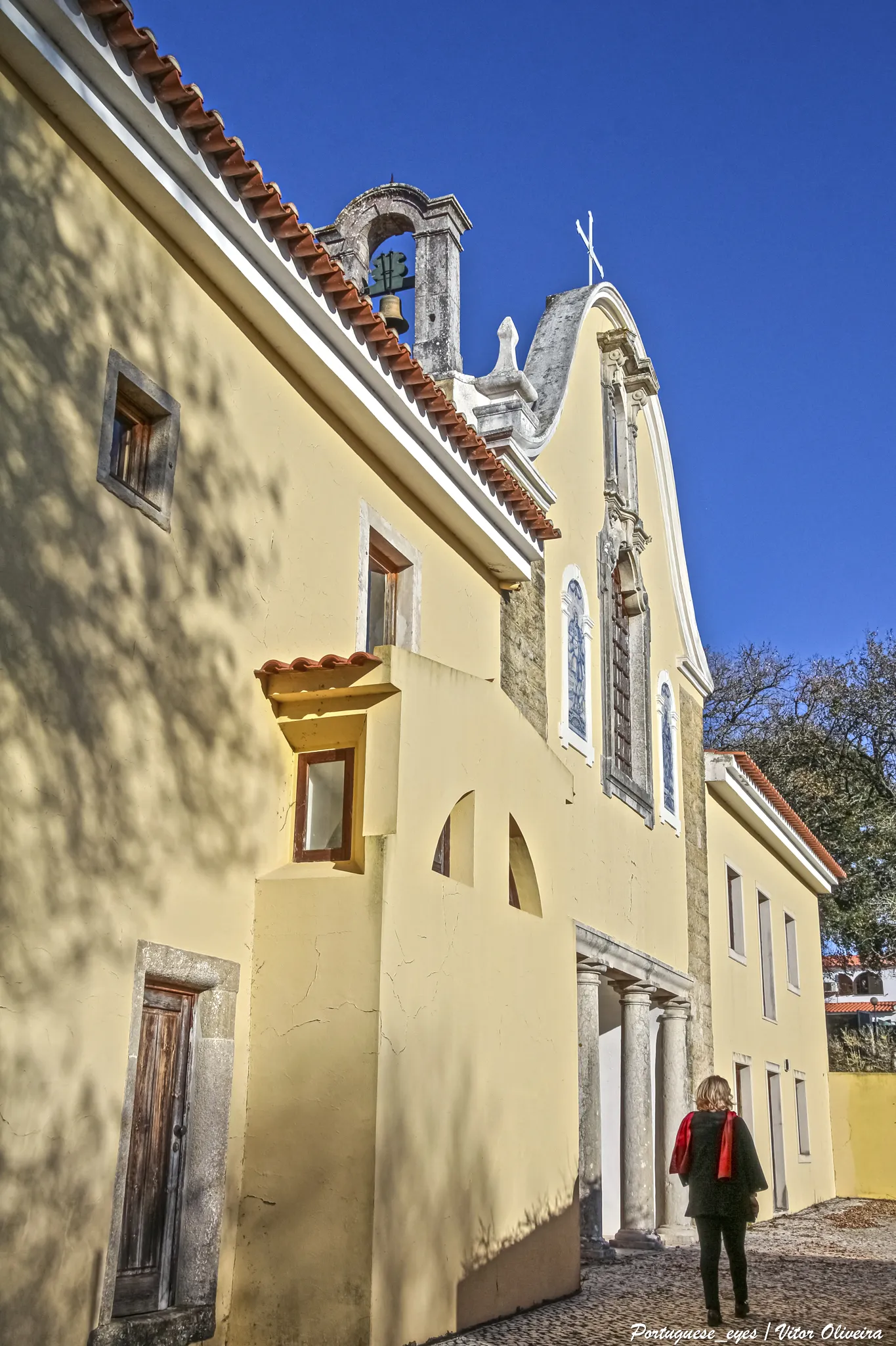 Photo showing: Ao longo dos tempos os arredores de Óbidos foram muito procurados para a implantação de ordens religiosas. Os Franciscanos Arrábidos foram os que conseguiram sobreviver.
Data do século XVI a sua implantação, tendo sido a 29 de Setembro de 1569 (dia do Arcanjo S. Miguel), lançada a primeira pedra para o seu convento, que, segundo dados escritos, foi seu fundador o Cardeal Infante D. Henrique. A construção foi instituída no Arelho, sendo um edifício muito pobre, mas em tudo seguindo os exemplos da tipologia geral da Ordem. Os monges davam uma verdadeira imagem de “pobreza franciscana”.
Os frades arrábidos fazem a sua entrada em Portugal no século XVI, sendo o primeiro convento instituído na Serra da Arrábida, fornecendo-lhes, para além do nome, uma tipologia de lugares preferenciados a habitar.
Voltando ao convento do Arelho, tinha quase tudo para estar no local ideal. Isolado, mas não em demasia, pois os frades para sobreviverem pediam nas povoações vizinhas (Óbidos e arredores). Ficavam perto da Lagoa, de onde obtinham o pescado. Mas havia um senão neste lugar, as más condições climáticas, sempre sujeito às humidades marítimas que abalavam a saúde dos religiosos. Por este motivo foi feita a transferência para as Gaeiras.
O desejo é conseguido quando D. Dinis de Lencastre, Alcaide de Óbidos e Comendador da Ordem de Cristo e sua mulher D. Isabel Henriques, se propõe oferecer novo convento, dada a grande devoção que tinham pela Ordem. A oferta é aceite e os doadores compram o terreno nas Gaeiras onde hoje se situa, tendo sido iniciada a construção em 1602 e, em 1606 já se faziam ofícios religiosos na capela-mor.
Foram sempre em número reduzido os religiosos deste convento, sendo inicialmente treze e mais tarde vinte.
Ao longo dos tempos as obras de restauro sucederam-se e em 1692 é pela primeira vez reedificado. Era um edifício com as habituais dependências conventuais, ou seja, das oficinas ao dormitório, passando pela capela e respirando o bom ar puro do pátio interior ou da cerca repleta de arvoredos. A calma do lugar convidava os monges e outras pessoas para um passeio de reflexão ou para agradáveis momentos de música. O cenário era completado por horta, pomares de fruta e uma fonte de água fresca (datada de 1702).
A sua construção é tipicamente de convento franciscano. A fachada da igreja tem uma galilé coberta, situando-se ao fundo de um adro de romaria. Ladeando a porta estão dois nichos de azulejos com figuras representativas de atos religiosos, sendo à esquerda o monge franciscano-capucho, de olhos vendados, cadeado na boca e fechadura no peito e, à direita, uma representação de S. João Baptista. Sobre a janela do coro, também em azulejos, as figuras de S. Roque e S. Barnabé e, em pedra, uma escultura de S. Miguel do século XVIII. Na portaria, numa espécie de altar, um grupo de imagens de barro, em tamanho natural, representam a morte de S. Francisco e, as ombreiras e vergas das portas são lavradas por inteiro e todas diferentes. O pátio interior é pequeno e singelo, de pilares simples, com fonte central e com uma pequena capela de teto em abóboda pintada e com um altar. A igreja, de uma só nave, abóboda caleada, constituída por dois altares laterais, coro com cadeirado e púlpito, ornado de azulejos pintados a azul sobre esmalte branco, representando a vida de S. Francisco e Santo António. No retábulo do altar-mor uma pintura seiscentista representa S. Miguel, ladeada por ornamentos de talha dourada.
Festa dos Cavaleiros

Era costume, que datava da fundação do Convento de São Miguel das Gaeiras, que na véspera de São João fosse àquele convento a Câmara de Óbidos com todos os empregados da justiça, que eram e tinha sido, e convidados da Câmara pela forma seguinte: - Na véspera de São João, pelas quatro horas da tarde, começava o sino do paço do concelho a tocar até que estivesse tudo pronto, e montavam a cavalo, indo [a] diante o porteiro, atrás os empregados, como escrivães, avaliadores do concelho, almotacés, e convidados, todos a dois e dois, e atrás de tudo a Câmara, de capas, com chapéus pequenos com a aba da parte de diante levantada e guarnecida de plumas brancas, indo adiante da câmara o procurador do concelho com o estandarte. E nesta forma partiam para o convento. E logo que ali chegavam, se dirigiam à igreja, onde todos faziam oração, e voltavam logo depois, pela mesma ordem, para Óbidos. No dia seguinte, pelas nove horas, tornava a tocar o sino do paço do concelho e se juntavam novamente, como no dia antecedente, e pela mesma ordem partiam os cavaleiros para o convento, onde iam ouvir missa e jantavam todos, para ajuda do qual a câmara era obrigada a dar aos frades dois carneiros, seis alqueires de trigo e dois almudes de vinho, o que nada era em relação ao que os frades apresentavam. Findo o jantar e lá pela tarde, iam à igreja buscar o estandarte, que ali tinha ficado do dia antecedente, e com coroas de flores enfiadas no braço direito partiam os cavaleiros pela mesma forma para Óbidos, vindo pela calçada, direitos à porta da Vila e dali à praça, depois davam três voltas pelas ruas principais da Vila e afinal se apeavam à porta do paço do concelho. Não era isento desta função qualquer que fosse ou tivesse sido empregado público. www.jf-gaeiras.pt/Convento_Sao_Miguel