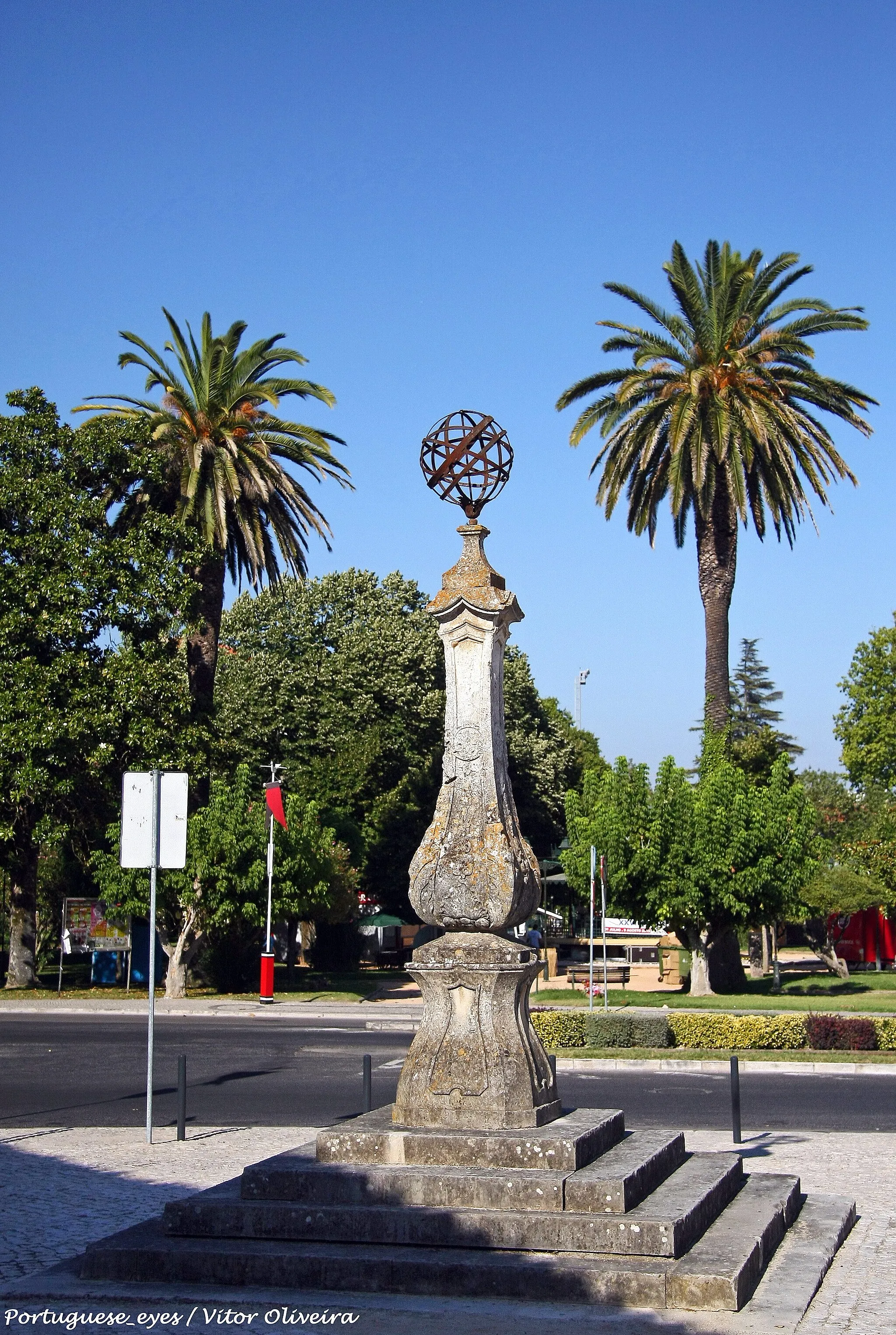 Photo showing: Tomar foi conquistada ao domínio árabe por D. Afonso Henriques, em 1147, e doada aos cavaleiros templários em 1159. Estes, na pessoa de D. Gualdim Pais, outorgaram à povoação as duas primeiras cartas de foral, uma datada de 1162 e outra de 1174. A partir do século XIV, veio a pertencer à Ordem de Cristo. Recebeu foral novo de D. Manuel, dado em 1510, e foi elevada à categoria de cidade em 1843, por D. Maria II. 
A cidade conserva um pelourinho, erguido no século XVII, certamente em substituição de outro mais antigo. Levanta-se no largo do mesmo nome, sendo resultado de uma reconstrução datada de 1939-40, visto que o monumento fora demolido em 1870. Sabe-se que em 1628 se encontrava ao fundo da Rua da Graça, e que sofreu restauro em 1839; mas após a demolição as peças andaram perdidas, chegando a servir de base para um candeeiro público. Na reconstrução foi possível reunir todos os elementos originais, à excepção do pedestal. 
O pelourinho assenta em plataforma de cinco degraus quadrangulares, de aresta, de factura moderna. É constituído por base, fuste e remate de feição barroca, de grande efeito cenográfico. A coluna assenta num grande pedestal de secção quadrangular, tornado octogonal através do ligeiro chanfro das arestas, tendo os quatro lados maiores moldurados e perfil bojudo. Este pedestal é encimado por uma peanha de cujo centro irrompe o fuste, em largo bojo decorado por molduras, volutas e concheados barrocos, que se adelgaça até ao topo. Não existe capitel, mas apenas uma cornija ligeiramente saliente, de lados quebrados. O remate é constituído por uma esfera armilar de grandes dimensões, em ferro, sobre coruchéu rústico.

Sílvia Leite www.patrimoniocultural.gov.pt/pt/patrimonio/patrimonio-im...