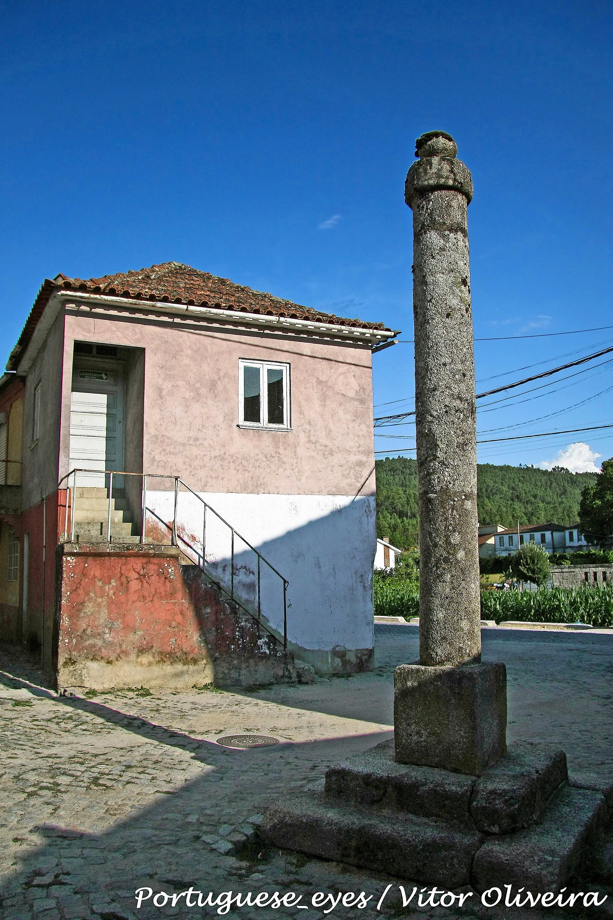 Photo showing: Estrutura em cantaria de granito, composta por soco quadrangular de dois degraus escalonados, onde assenta a base, na forma de plinto cúbico. Fuste cilíndrico, liso, composto por três tambores de altimetria desigual. Remate em forma de capelo encimado por uma maçaneta ou esfera achatada. A face S. do plinto apresenta pequeno registo azulejar figurativo azul e branco com imagem de Nossa Senhora aureolada com uma fita que contém a legenda "VIRGEM EMACULADA SENHORA NOSSA". Acantonados superiormente um escudo de Portugal-antigo e a legenda "AV MAR IA", nos flancos as datas de "1646" e "1946". Inferiormente, outra legenda "HA 3 SÉCULOS VOS PROCLMAMOS PADROEIRA". No lado E. do fuste, a 2 m. de altura, três perfurações em triângulo, onde estiveram cravados ferros de sujeição. www.monumentos.pt/Site/APP_PagesUser/SIPA.aspx?id=4998

See where this picture was taken. [?]