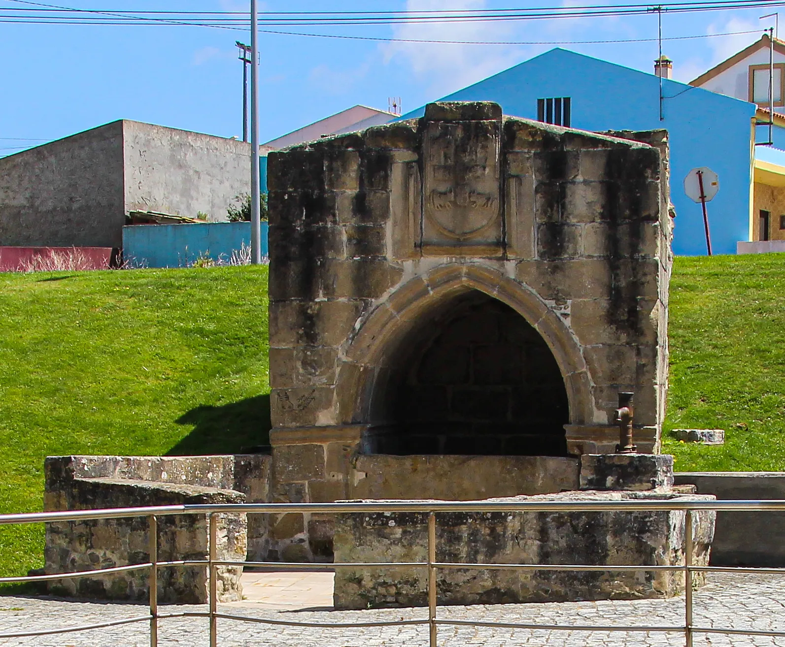 Photo showing: A Fonte de Nossa Senhora da Conceição, construída no Século XIV (provável), encontra-se a poucos metros da Igreja com o mesmo nome sendo conhecida também por Fonte Gótica, Fonte do Infante (topónimo constatado em documentação setecentista) ou Fonte dos Gafos, devido à existência de uma Gafaria à data da sua construção.
A fonte, cujo serventia é enquadrada por um arco de ogiva, coroado por um brasão ostentanto as antigas armas da vila, apresenta traços de uso como lavadouro, beneficiando hoje no seu repouso, do enquadramento do ajardinamento que lhe foi oferecido.
Cronologia
1165 - Povoada a vila por Wilhelmo Lacorne, fidalgo francês, como prémio de ter ajudado D. Afonso I na tomada de Lisboa;
1167 - Foral dado por D. Afonso I;
1218 - Foral confirmado por D. Afonso II;
1313 - provável da construção da fonte, mandada erigir pela Rainha Santa Isabel, que viveu na Atouguia nessa data; também conhecida por Fonte dos Gafos, por ter sido construída perto da fonte uma Gafaria, onde existia um grande tanque no qual eram banhados os doentes antes de entrarem no albergue;
1373 e 1376 - Cortes celebradas no reinado de D. Fernando;
1510 - Foral novo dado por D. Manuel em Santarém;

1759 - D. José I manda justiçar o último www.jf-atouguiadabaleia.pt/patrimonio/FONTE-DE-NOSSA-SENH...