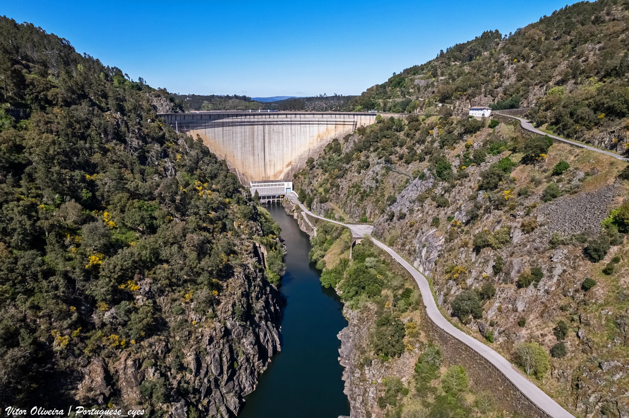 Photo showing: A barragem do Cabril no rio Zêzere é uma das maiores barragens portuguesas e origina uma da maiores reservas de água doce do país. É uma das mais altas construções de Portugal.
A construção da Barragem do Cabril teve início em Abril de 1951, com a obra a cargo da Hidro Eléctrica do Zêzere e projecto de Joaquim Laginha Serafim[1]. A inauguração teve lugar no dia 31 de Julho de 1954 e contou com a presença do Presidente da República, General Craveiro Lopes[2].
A barragem é do tipo arco abóbada, com uma altura de 136 metros e com 200 metros de comprimento do coroamento. A capacidade de descarga é de 2 200 m³/s.
A sua albufeira tem uma capacidade total de 720 000 (*1000 m³), enquanto a sua capacidade útil é de 615 000 (*1000 m³). O seu perímetro é de 280 km.
Esta albufeira oferece um dos melhores quadros turísticos do concelho e as suas águas são procuradas para actividades aquáticas e pelos amantes da pesca desportiva.
O arco da barragem do Cabril é atravessado pela Estrada Nacional 2 (EN2), a estrada mais longa de Portugal[3].
Albufeira
Capacidade Total da albufeira: 720 000 (*1000 m³)
Capacidade Útil: 615 000 (*1000 m³)
Volume Morto: 105 000 (*1000 m³)
Cota do Nível de Pleno Armazenamento: 296 (m)
Cota do Nível Mínimo de Exploração: 240 (m)
Superfície inundável à cota de pleno armazenamento: 2023 (ha)
Perímetro: 280 km
Bacia hidrográfica
Sub-Bacia Hidrográfica Principal: Rio Zêzere
Área da Sub-Bacia Hidrográfica Principal: 2414.45 (km²)
Área da Sub-Bacia Hidrográfica Própria: 2292.82 (km²)
Precipitação Média da Bacia Hidrográfica: 1300 (mm)
Características Fisiográficas da Bacia Hidrográfica
Altitude média: 633.06 (m)
Declive médio: 24 (%)
Escoamento Médio Anual: 965 (hm³)
Caudal Máximo de Cheia: 2200 (m³/s)
Barragem
Ano entrada em funcionamento: 1954
Tipo de Barragem: Arco Abóbada
Altura da Barragem: 136 (m)
Comprimento do Coroamento: 290 (m)
Tipo do Descarregador: Orifício
Capacidade do Descarregador: 2 200 (m³/s)

pt.wikipedia.org/wiki/Barragem_do_Cabril