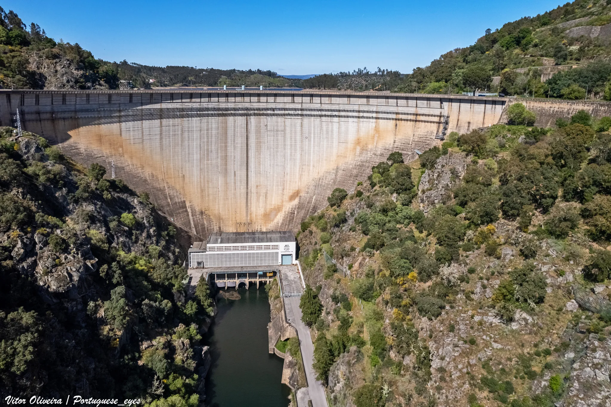 Photo showing: A barragem do Cabril no rio Zêzere é uma das maiores barragens portuguesas e origina uma da maiores reservas de água doce do país. É uma das mais altas construções de Portugal.
A construção da Barragem do Cabril teve início em Abril de 1951, com a obra a cargo da Hidro Eléctrica do Zêzere e projecto de Joaquim Laginha Serafim[1]. A inauguração teve lugar no dia 31 de Julho de 1954 e contou com a presença do Presidente da República, General Craveiro Lopes[2].
A barragem é do tipo arco abóbada, com uma altura de 136 metros e com 200 metros de comprimento do coroamento. A capacidade de descarga é de 2 200 m³/s.
A sua albufeira tem uma capacidade total de 720 000 (*1000 m³), enquanto a sua capacidade útil é de 615 000 (*1000 m³). O seu perímetro é de 280 km.
Esta albufeira oferece um dos melhores quadros turísticos do concelho e as suas águas são procuradas para actividades aquáticas e pelos amantes da pesca desportiva.
O arco da barragem do Cabril é atravessado pela Estrada Nacional 2 (EN2), a estrada mais longa de Portugal[3].
Albufeira
Capacidade Total da albufeira: 720 000 (*1000 m³)
Capacidade Útil: 615 000 (*1000 m³)
Volume Morto: 105 000 (*1000 m³)
Cota do Nível de Pleno Armazenamento: 296 (m)
Cota do Nível Mínimo de Exploração: 240 (m)
Superfície inundável à cota de pleno armazenamento: 2023 (ha)
Perímetro: 280 km
Bacia hidrográfica
Sub-Bacia Hidrográfica Principal: Rio Zêzere
Área da Sub-Bacia Hidrográfica Principal: 2414.45 (km²)
Área da Sub-Bacia Hidrográfica Própria: 2292.82 (km²)
Precipitação Média da Bacia Hidrográfica: 1300 (mm)
Características Fisiográficas da Bacia Hidrográfica
Altitude média: 633.06 (m)
Declive médio: 24 (%)
Escoamento Médio Anual: 965 (hm³)
Caudal Máximo de Cheia: 2200 (m³/s)
Barragem
Ano entrada em funcionamento: 1954
Tipo de Barragem: Arco Abóbada
Altura da Barragem: 136 (m)
Comprimento do Coroamento: 290 (m)
Tipo do Descarregador: Orifício
Capacidade do Descarregador: 2 200 (m³/s)

pt.wikipedia.org/wiki/Barragem_do_Cabril