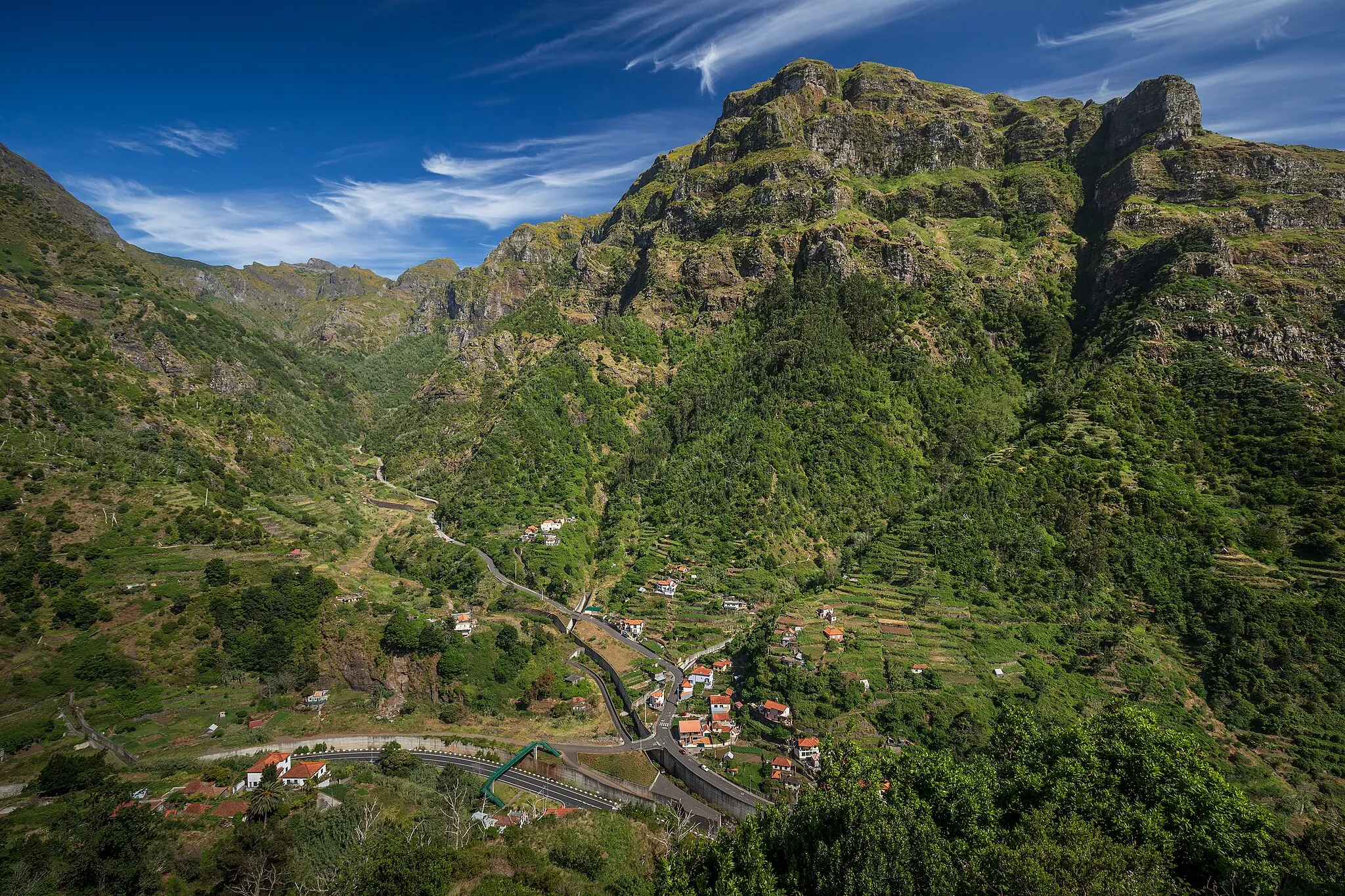 Photo showing: A view from Miradouro de Terra Grande towards the valley of Ribeira do Pico in Ribeira Brava, Madeira, Portugal in 2023 May. The village below is Ameixieira. The mountain above is Pico da Cruz. The valley below is Vale da Ribeira Brava.