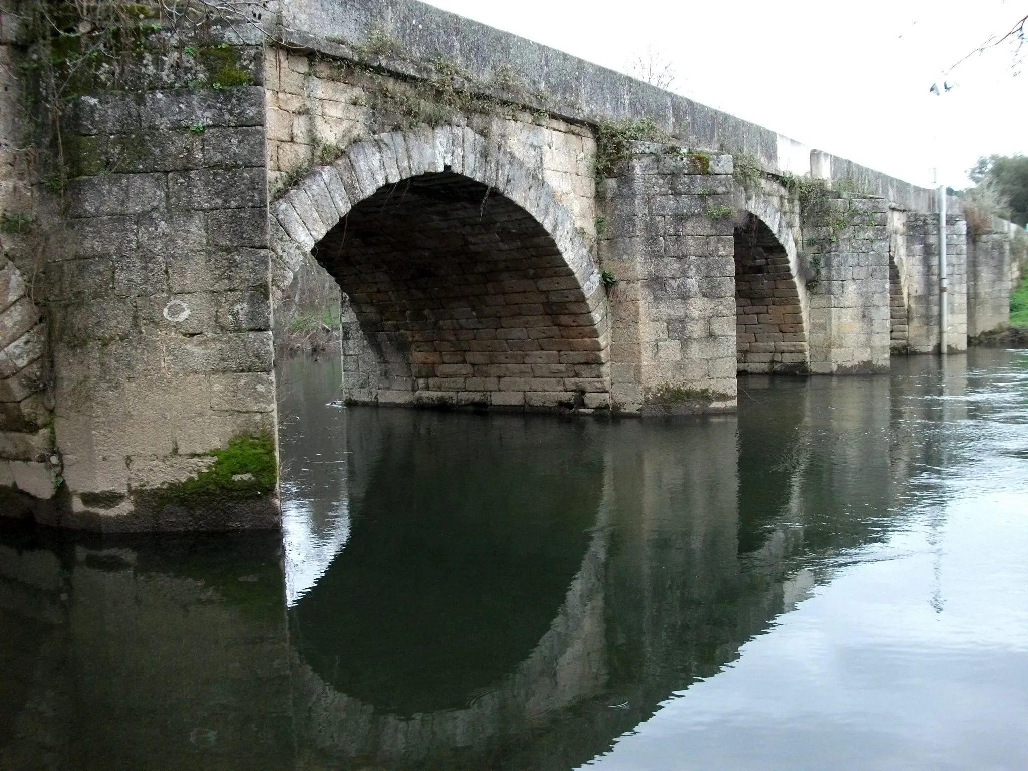 Photo showing: Vista a jusante da margem direita da "Ponte de pedra sobre o rio Tuela", também referida como "Ponte Românica sobre o rio Tuela" ou "Ponte de Torre de Dona Chama", na Estrada Nacional 206 em Torre de Dona Chama, Portugal.