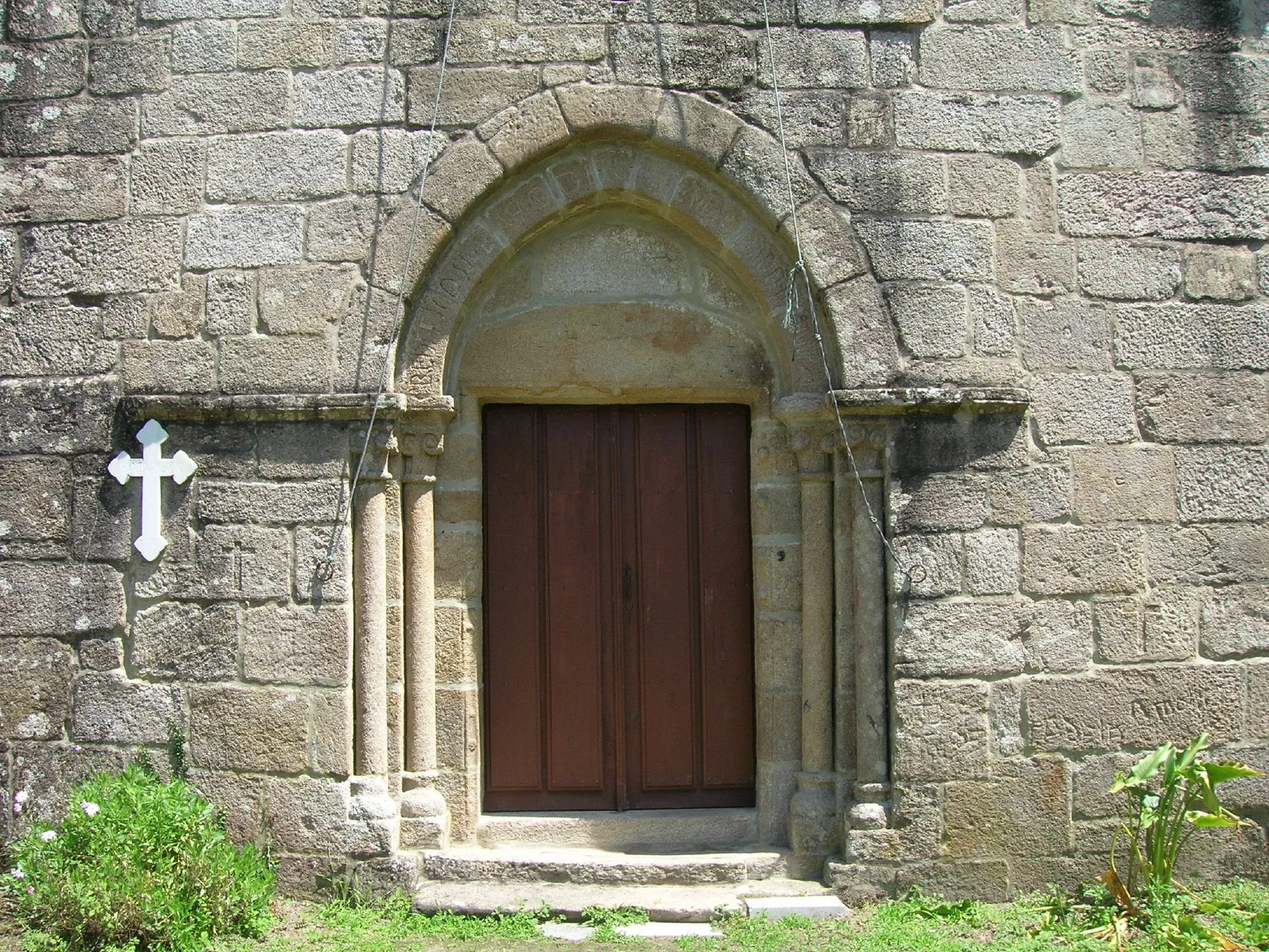 Photo showing: La portada principal responde a un esquema típicamente románico, con los arcos ligeramente apuntados, apoyándose ambos en dos pares de columnas acodilladas.