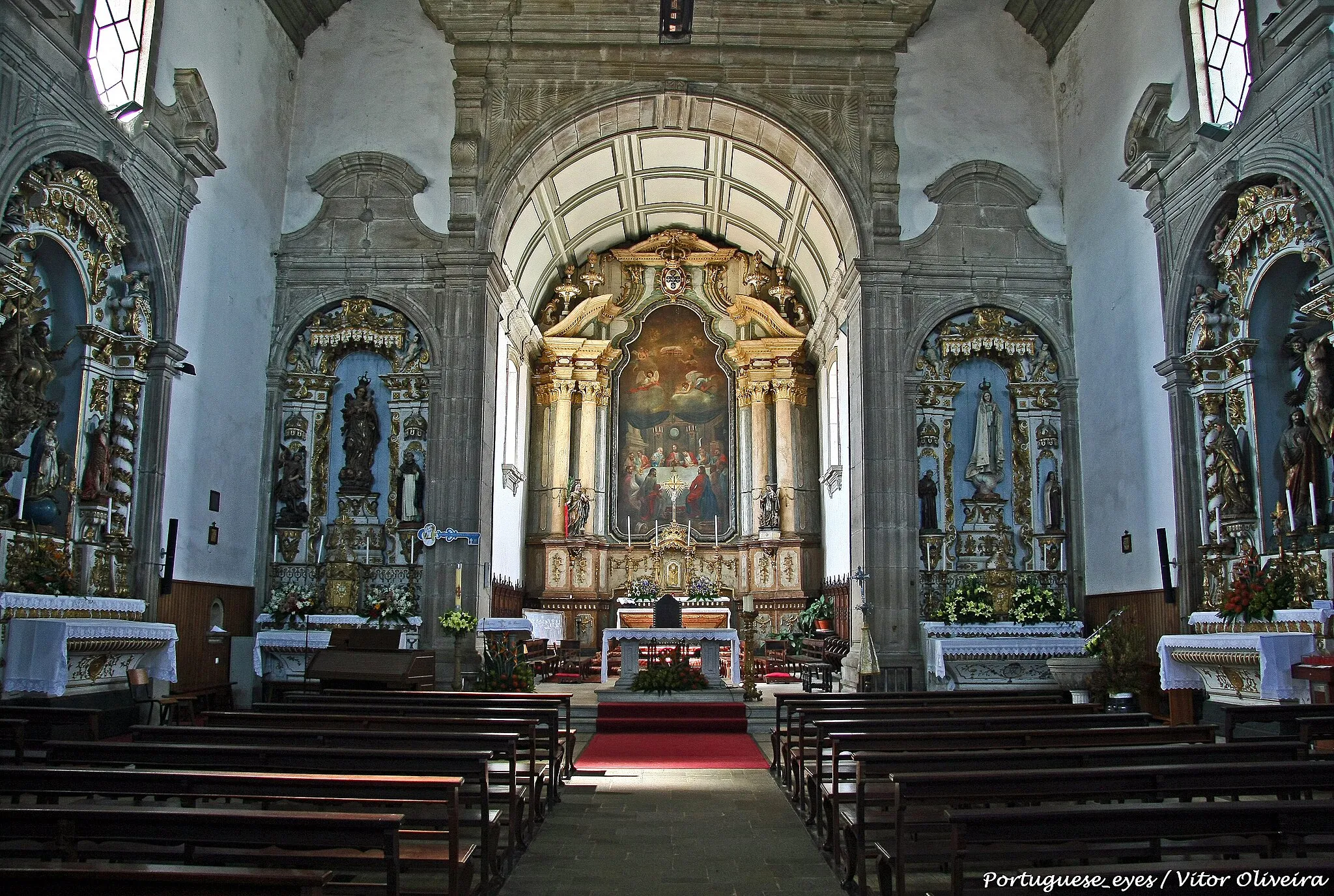 Photo showing: Planta longitudinal, composta por duplo rectângulo, de uma só grande nave e capela-mor, enquadrado por duas torres de secção quadrada. Dois outros corpos baixos, das sacristias, flanqueiam a capela-mor. Os vários corpos são volumetricamente distintos, com coberturas diferenciadas em telhados de 2 águas e domo nas torres sineiras. Fachada principal, harmónica, divide-se em três panos através de pilastras toscanas; composição portal axial enquadrado por pilastras almofadadas e cornija simples; sobrepõe-se grande cartela oval, sem legenda, terminado em pequena arquitrave; nicho fechado com vidro, enquadrado de pequenas pilastras contendo imagem de Santa Marinha; óculo quadrilobado remata a composição; enquadrando lateralmente o nicho, duas janelas ovais. Todos estes elementos são rebordados de aletas e de outras decorações. Corre sobre as pilastras, entablamento cuja cornija se recurva em traçado mistilíneo na parte central da empena onde se abre varanda com guarda de balaústres; aos lados, levanta-se o segundo corpo das torres, de uma ventana de cada lado, pilastras nos cunhais e entablamento, pináculos nos ângulos e cobertura hemisférica. Fachadas laterais com pilastras nos cunhais e cornija; porta travessa, rectangular, de pilastras dóricas, entablamento e frontão interrompido; no alto, 4 janelas. Na capela-mor, abrem-se em cada lado 2 janelas amplas, adossando-se-lhe perpendicularmente os corpos, de um piso, das sacristias; empena posterior de recorte mistilíneo semelhante ao da frontaria, com fogaréus sobre as pilastras e cruz na empena. INTERIOR com coro-alto sobre arco abatido, tendo no 1º registo das torres o baptistério no lado do Evangelho e a escada de acesso ao coro no lado da Epístola. Nave percorrida com lambril de madeira. Quatro capelas colaterais, 2 de vão recto e frontão de volutas interrompidas, iguais a 2 portas que se lhe seguem, e outras 2, de vão curvo, contendo retábulos de talha branca e dourada. Dois altares laterais de arco pleno e frontão curvo. Dois púlpitos com bacia de pedra sobre composição com 3 mísulas e guardas de madeira. Arco triunfal alto com pilastras e entablamento, frontão interrompido com os ramos enrolados enquadrando janela no coroamento. Outros 4 arcos existem cavados nas paredes sendo 2 colaterais, concatenando-se com o cruzeiro, e 2 nos flancos junto aos ombros. Tecto em 7 séries de 14 caixotões com fortes divisões apenas molduradas. Capela-mor com cadeiral e retábulo de largo camarim com tela figurando última ceia entre 4 colunas exibindo no alto remate o escudo nacional e tecto de caixotões lisos. www.monumentos.pt/Site/APP_PagesUser/SIPA.aspx?id=260