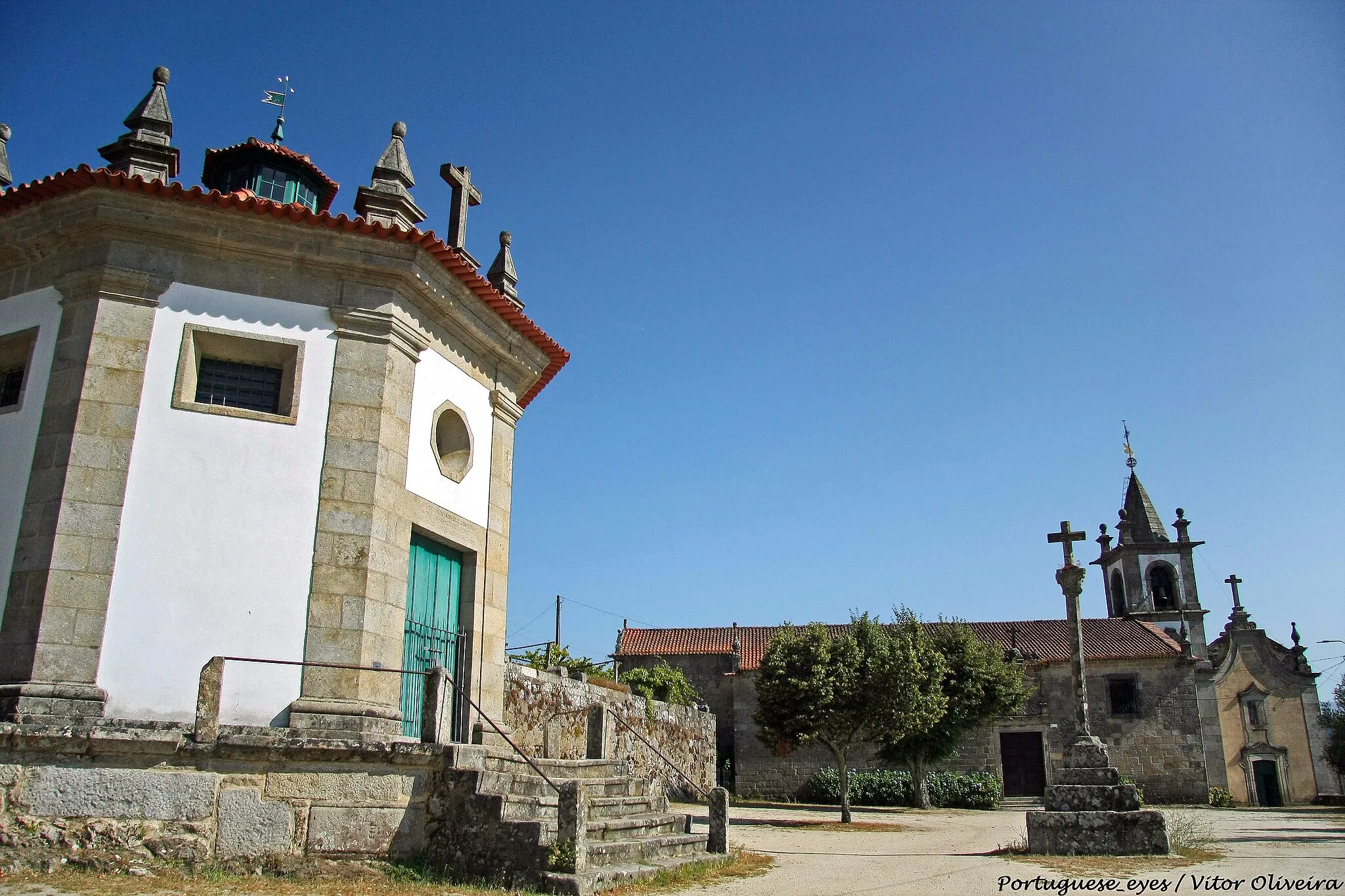 Photo showing: Apesar de se desconhecer a data da sua fundação, sabe-se que em 1120 este Mosteiro pertencia já à Diocese do Porto, estando ligado aos Cónegos Regrantes de Santo Agostinho. Em 1141, D. Afonso Henriques vende a Carta de Couto ao abade do Mosteiro por 150 morabitinos. Em 1560, é anexado ao Convento de S. Domingos de Lisboa, por decisão do Papa Pio IV. No século XVIII constroem-se vários edifícios que ainda hoje notabilizam este conjunto arquitectónico: os Celeiros e a Adega, a Capela octogonal de Nosso Sr. do Bom Despacho e, provavelmente, o Fontanário. Nos inícios do séc. XIX, o Mosteiro foi vendido em hasta pública, ficando na posse do barão de Ancede.

Mosteiro de Ancede
Do séc. XII aos finais do séc. XIV
O primeiro documento conhecido que faz referência ao Mosteiro de Sto. André de Ancede data de 1120, sendo naturalmente anterior a sua fundação, e dá-nos conta da sua filiação na Ordem dos Cónegos Regrantes de Sto. Agostinho. A partir de 1123, pela mão de Calisto II, passa a estar ligado à igreja do Porto.
Do primitivo mosteiro apenas resta hoje alguns paramentos e a rosácea, com um espesso toro na face externa, delimitada por duas pequenas escócias e uma orla perolada que é já obra do séc. XIII (BARROCA, 1984, 129).
D. Afonso Henriques passa carta de couto ao mosteiro a partir de 1141 em troca de 150 morabitinos. Pela descrição da área coutada, podemos verificar que se trata já de uma propriedade com alguma dimensão a nível local (cerca de 16 km2), mas longe ainda do peso económico que esta casa irá adquirir ao longo de toda a Baixa Idade Média. Este crescimento económico deveu-se a uma ampliação sistemática do seu património fundiário, alcançada através da aquisição e aproveitamento de novas propriedades, de um conjunto significativo de doações e por vários escambos e aforamentos. O aproveitamento económico desse património foi conseguido, numa primeira fase, através sistemas de arrendamento adoptados e, numa outra fase, com base num esforço de comercialização de larga escala dos produtos vinícolas. Estas estratégias foram antecedidas duma aposta feita no vinho por ser um artigo rentável já na época. Assim, as terras eram exploradas por rendeiros, que eram submetidos a contratos agrícolas de certa forma rígidos por imporem o cultivo intensivo do vinho, técnicas e até estruturas de vinificação. A crescente produção de vinho facilitou a integração do Mosteiro de Ancede nos circuitos comerciais do Douro canalizados maioritariamente para a cidade do Porto.

Este processo de comercialização foi sendo facilitado graças aos lucros da venda do vinho, pois já na centúria de Trezentos, o Mosteiro de Ancede gozava do estatuto de vizinho da cidade do Porto, libertando-o de solicitar autorização para as exportações de vinho, de deixar 1/3 da produção a exportar e de vender obrigatoriamente na cidade. Este comércio de curta e de longa distância justifica e era facilitado pelos prédios urbanos da cidade do Porto, pelas adegas e pelos armazéns que o mosteiro possuía em Gaia e no Porto, bem como pelos barcos de alto bordo dirigidos por mareantes do Porto desde o séc. XV. As rendas e os impostos eram sempre pagos em vinho e não em dinheiro. A produção de vinho bem como serviços prestados pelos rendeiros eram encaminhados para propriedades de maiores dimensões (as granjas), como Ermêlo ou Quintela, que se encontravam dotados de equipamentos adequados à produção e ao armazenamento de vinho e de outros produtos (cereais, fruta, azeite, gado, mel, produtos de caça e de pesca).
O crescimento económico do Mosteiro permite que no final da Idade Média, a propriedade fundiária do mesmo se estenda de Baião a Mesão Frio, com prolongamentos até Penaguião, Cárquere (Resende) e Lamego, possuindo ainda propriedades em Trás-os-Montes, e sobretudo na Beira, para além dos bens imóveis anteriormente referidos em Gaia e no Porto, e de várias pesqueiras ao longo do Rio Douro. Os lucros do comércio do vinho permitiram ainda a realização de várias obras de valorização e de embelezamento nos espaços físicos do Mosteiro. Outras terão sido realizadas por vicissitudes sofridas como terá sido o caso do incêndio de 1355 que destruiu “o dormitório e as casas em redor dele, o refeitório, o cabide e a crasta”. Sabe-se ainda que em 1363 as obras de recuperação ainda não estavam concluídas.
Do séc. XV aos nossos dias
Na 2ª metade do Séc. XVI, o Mosteiro atravessava uma fase de decadência visível no número reduzido de monges que aí habitava, estando a gestão do seu património entregue a um comendatário. Em 1560 por solicitação de D. Catarina da Áustria, então Regente do Reino, o Papa Pio IV, edita a bula que permite a anexação do Mosteiro de Ancede pelo Convento de S. Domingos de Lisboa. No entanto, o Mosteiro continuou a produzir vinho de qualidade que passou a ser encaminhado por mar para sustento da casa-mãe em Lisboa (BARROS, 1998), tendo sido na centúria de Quinhentos que se embelezou os espaços do Mosteiro ao adquirir várias obras de arte. Destas destaca-se o belíssimo tríptico flamengo da autoria de Joos van Cleve de 1530 (LORENA, 2016).
No séc. XVII fazem-se já grandes obras de remodelação ao substituírem as duas igrejas que faziam parte do Mosteiro por um novo edifício de três naves com três capelas ornamentadas e com um coro, tendo sido concluída em 1689 (Livro 3529, fólio 43 verso e fólio 44, de 1746). Esta descrição corresponde ao aspecto actual da igreja de Ancede. A igreja da freguesia era composta por duas naves, o que pressupõe dimensões mais modestas. Datará também do séc. XVII a cerca do Convento de Ancede, uma vez que nos surge num documento a referência de que no ano de 1692 o convento se encontrava já “tapado de muro em toda a roda” (Livro 3529, fólio 45, de 1746)
No século XVIII, o então Convento de Ancede deve ter continuado a viver um período de expansão económica pois datam dessa época grandes obras de remodelação, como sendo a construção dos Celeiros e da Adega (em 1722), a construção da Capela do Senhor do Bom Despacho em 1731, e por fim o Portal Norte em 1735, portal que fecha este conjunto ao ter sido construído acoplado a uma das paredes da capela e do Celeiro. No entanto, o Auto de mediação da Igreja, convento e cerca datado de 1745, refere que a torre ameaçava ruir, pelo que se encontrava parcialmente demolida. A ala poente do Mosteiro é tida como sendo muito antiga, ainda do tempo dos cónegos. Aí se localizava a livraria e 6 celas.
A ala sul é já referida como a ala nova, onde se localiza, no andar inferior e na direcção de nascente a poente, a sala “de profundiz”, o refeitório e a despensa. No andar superior, localizava-se a barbearia e 3 celas, uma das quais “assistiam os padres procuradores”. Na ala nascente, localizava-se a casa do despacho, a cela dos procuradores gerais e mais duas celas. Nesse documento, é descrito o claustro fechado “com telheiro” em toda a volta com excepção do lado norte (igreja), apoiado em colunas de pedra. O pavimento é descrito como sendo todo em terra, com sepulturas junto da sacristia e da igreja.
A Casa da Hospedaria e a Casa dos Moços, corresponde, grosso modo, ao edifício que serviu como casa de caseiro. No séc. XVIII, era um edifício de maiores dimensões tendo-se detectado nas escavações realizadas em 2005 o limite exterior, localizado a sul da atual parede exterior. A seguir a esta, em direcção a nascente, localizava-se a casa do lagar e a do forno, que com os seus alpendres, fechavam o pátio, encostando ao Fontanário.
Com a expulsão das Ordens Religiosas em Portugal durante a 1ª metade do séc. XIX, o Convento foi vendido em hasta pública, ficando na posse do Barão de Ancede, que aí faz um colégio para raparigas. Na fachada do portão norte é ainda visível o seu brasão. Como a Igreja e a Capela ficaram à margem deste processo de venda, foram restituídas à Paroquia em 1932.
Algumas reflexões sobre o Conjunto Arquitectónico de Ancede 
No artigo citado de Amândio Barros podemos depreender que foram várias as obras e os melhoramentos que este Mosteiro sofreu ao longo dos dois séculos sobre os quais este historiador se debruçou. No entanto, está por fazer a História arquitectónica deste importante edifício e de todas as estruturas anexas. O aspecto exterior da Igreja parece inserir-se no estilo arquitectónico conhecido como “estilo chão” que se caracteriza por um despojamento decorativo, por volumetrias quadrangulares e por uma sobriedade e rigor geométrico que tão bem se enquadra em estilos de gosto clássico, como o foram o Renascentismo, o Maneirismo e mais tarde o Neoclassicismo. Este estilo chão manifestou-se em Portugal desde os finais do séc. XVI e perdurou até aos finais do século XVII.
Apesar de serem posteriores, o edifício do Celeiro, o Fontanário e o Portal Norte parecem inserir-se no mesmo estilo arquitectónico. Podemos estar a assistir a uma perduração deste estilo nos inícios do século XVIII. Note-se ainda a preocupação em manter a simetria da fachada no grande edifício do Celeiro. Essa simetria foi alcançada pela colocação das pilastras, independentemente da divisão interna que se efectuou no corpo do edifício. Os Celeiros exibem a data de 1722, a capela octogonal do Senhor do Bom Despacho data já de 1731 e o portal que fecha todo este conjunto construído acoplado à Capela e ao grande edifício que terá funcionado como armazém ostenta a data de 1735 e o brasão do Barão de Ancede. A sobriedade exterior da Capela octógonal contrasta profundamente com a decoração do seu interior, onde predomina o estilo barroco.
Apesar do portal ter sido construído pouco depois dos Celeiros, o facto de o ter sido acoplado à parede externa da fachada desse edifício, faz com que passe a perturbar a sua leitura, ao desrespeitar a preocupação de simetria e de rigor geométrico tido na sua construção. Somos então da opinião que se assiste em Ancede a uma perduração deste estilo nos inícios do século XVIII, sobretudo no que diz respeito à decoração das fachadas, ao manterem o mesmo tipo de pináculos, as pilastras e as volutas que também caracterizam a Igreja de Ancede, cuja conclusão data de 1689.
O fontanário deverá também ter sido construído pela mesma altura a avaliar pela sua decoração, mas também pelo sítio em que foi implantado. Todos estes edifícios: Celeiro, Adega, Fontanário e Capela foram certamente construídos com base num projecto global, já que obrigou ao corte do terreno, a um desaterro a nascente necessário à sua implantação. Ao mesmo tempo, o desaterro fez com que se aterrasse o patamar que medeia este conjunto e o da Igreja e ala nascente do Mosteiro, situadas a uma cota bastante inferior. Este aterro obrigou então à construção de um muro de suporte junto dessa ala nascente, que vem tapar as janelas da actual sacristia da Igreja.
A Capela do Senhor do Bom Despacho que se encontra no mesmo patamar da Igreja foi então construída adoçada a este muro de suporte.
BIBLIOGRAFIA:
BARROS, Amândio (1998). O património do Mosteiro de Ancede na Idade Média (séculos XII-XIV). In. Actas do Colóquio “Serra da Aboboreira e a região do Douro. Arqueologia e Natureza. Valores a potenciar”, ed. polic., Baião.
BARROCA, Mário Jorge (1984), Notas sobre a ocupação medieval em Baião, Arqueologia, 10, 129.
CÂMARA MUNICIPAL DE BAIÃO, Plano Director Municipal. Descritor do Património Cultural, ed. polic., Baião.
LORENA, Mercês. (2016). Tríptico do Mestre de Ancede. In. Joel Ferreira Mata, Baião: Em torno do ano 1500. (pp. 70-74). Casal de Cambra: Caleidoscópio.

PEREIRA, Fernando António Baptista (1992), História da Arte Portuguesa. Época Moderna (1500-1800). (pp. 42-92). Lisboa: Universidade Aberta. www.visitbaiao.pt/2017/05/09/6-mosteiro-de-santo-andre-de...