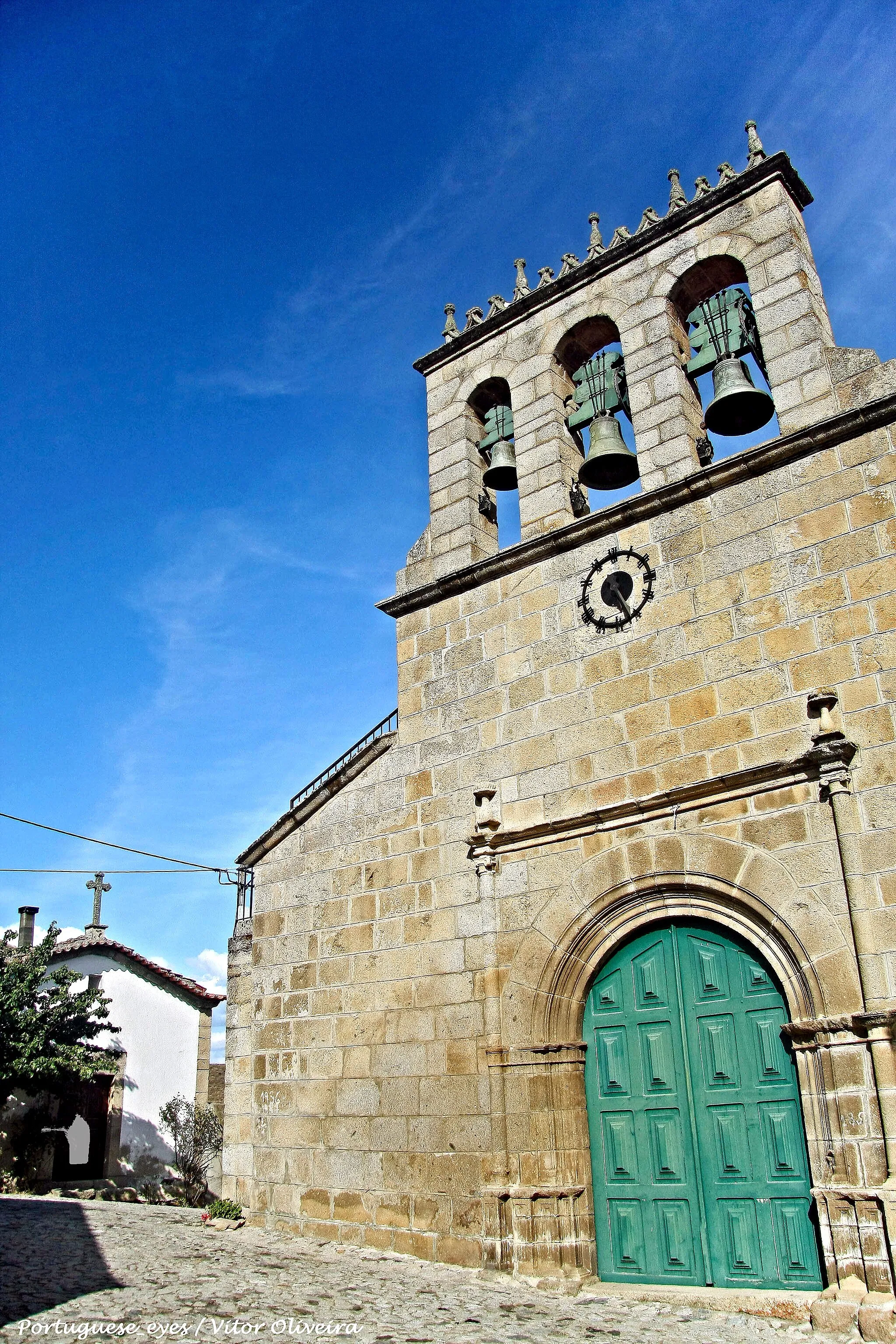 Photo showing: Igreja com uma fachada em silheira sem reboco e um campanário sobrelevado de três sineiras, que se destaca acima do edifício