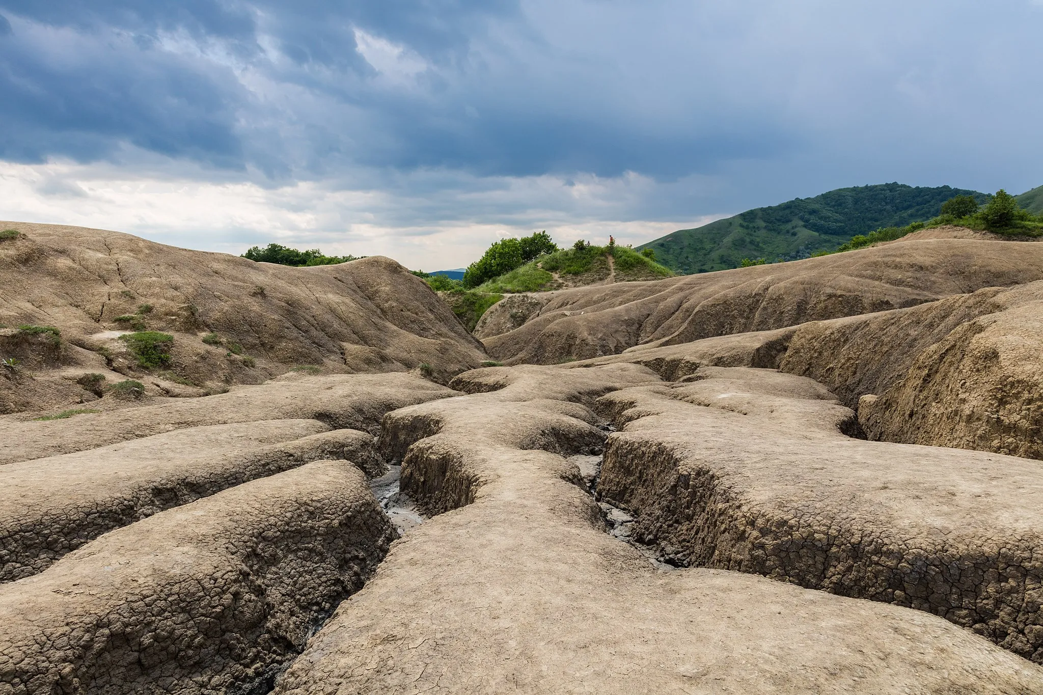 Photo showing: The Berca Mud Volcanoes are a geological and botanical reservation located close to Berca in Buzău County, Romania. The phenomenon is caused due to gases that erupt from 3,000 metres (9,800 ft) deep towards the surface, through the underground layers of clay and water, they push up underground salty water and mud, so that they overflow through the mouths of the volcanoes, while the gas emerges as bubbles. When the mud arrives at the surface, it dries off, changing the landscape in ways like you can see here.