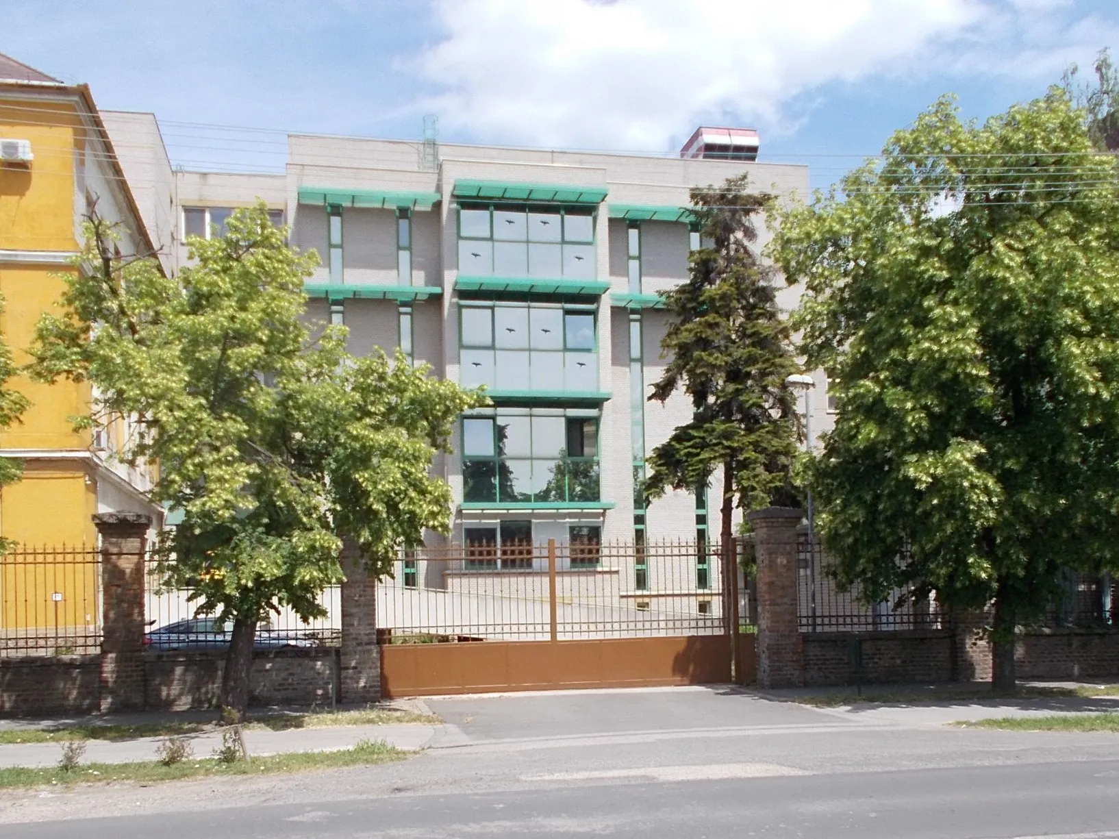 Photo showing: Gyula Hospital from Szent István Street. Official name since 2016: ~~Kálmán Pándy Member Hospital of the Hospital Békés County Central Hospital other/short name Kálmán Pándy Member Hospital or Kálmán Pándy County Hospital. The oldest part of the hospital on Semmelweis Street,-since 1840 hospital building,-signed with plaque. The washing building (built in the end of the 19th cent.) and the hospital chapel (early 20th century) are local grade listed monuments. There are a couple sculptures in between buildings and plaque-reliefs are building inside. There is a sizeable mushroom shaped water tower and a rooftop heliport (fifth grade) too. - 1 Semmelweis Street, bordered by/ or between Dob Street and Szent István Street, Magyarváros (lit. Hungarian Town) neighborhood, Gyula, Békés County, Hungary.