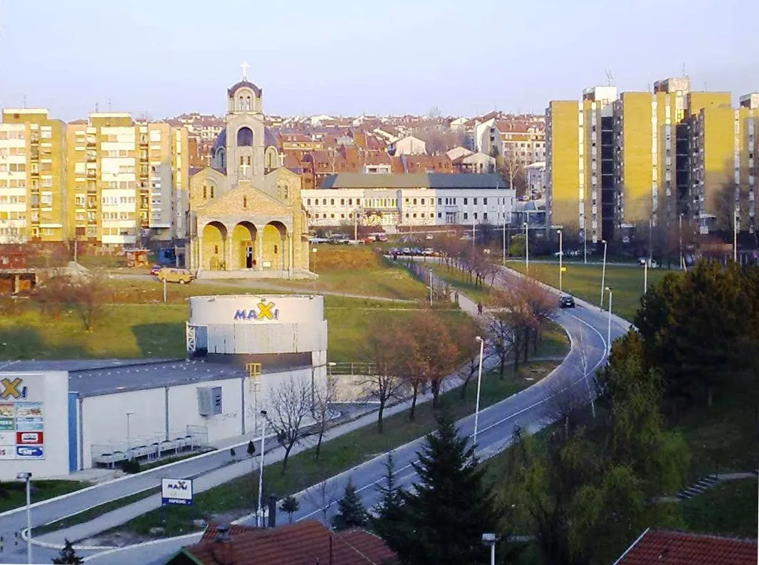 Photo showing: Uz ulicu Samjuela Beketa (eks Blaža Jovanovića) u Mirijevu, nalaze se neki važni objekti. Na uglu sa ul. Mirijevski venac je supermarket. Iznad se nalazi crkva (u izgradnji). Dalje i iznad je Dom zdravlja (duga, bela, dvospratna zgrada; u izgradnji). Preko puta (levo) od Doma zdravlja je Mirijevska pijaca (ne vidi se), oko koje se nalaze mnogi lokali. Još dalje u naselju je i Stanica Policije. Višespratnice između crkve i Doma zdravlja su karakteristične za Mirijevo II, a zgrade sa crvenim krovovima iza Doma su deo Mirijeva IV. Snimljeno 9.3.2008.