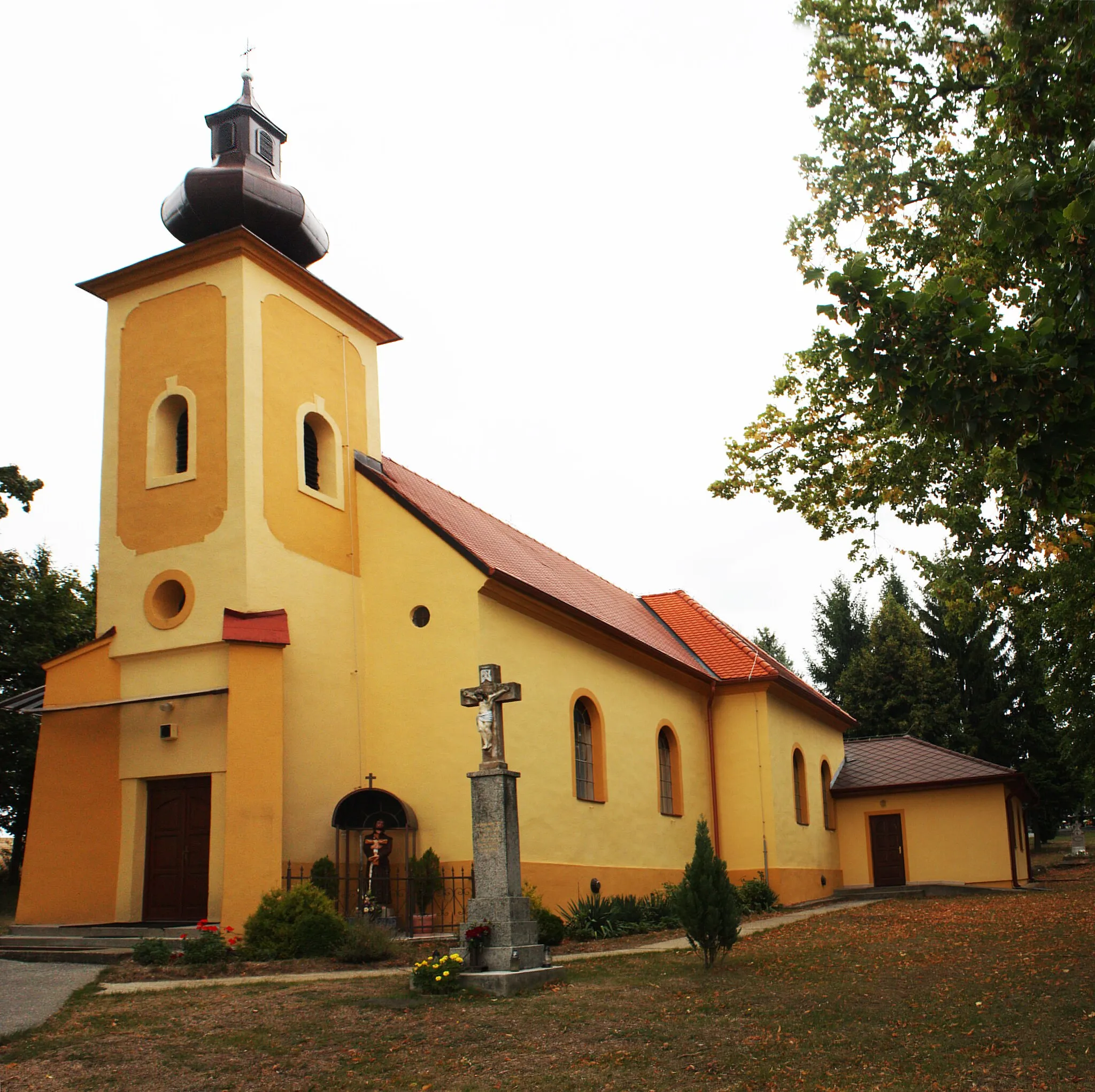 Photo showing: Kostol Najsvätejšej Trojice- katolícky, pôvodne barokový, postavený roku 1734 na staršom gotickom jadre, prestavaný v klasicistickom slohu v roku 1802. Reštaurovaný bol v roku 1936 a v roku 1992. V roku 1995 namiesto ukradnutého oltára bol postavený nový a v roku 2009 dostal kostol novú strechu. Zvon kostola pravdepodobne pochádza z jednej zo zaniknutých kaplniek hradu Gýmeš. 
A Szentháromság templom: római katolikus templom, amely eredetileg barokk stílusú volt. Egy gótikus kápolna alapjaira lett 1734-ben építve, majd 1802-ben klasszicista stílusú arculatot kapott.   Az eltulajdonított oltár helyére 1995-ben egy új került, 2009-ben pedig a templom tetőzetét felújították. A templom harangja a Gimesi vár egyik kápolnájából származik.