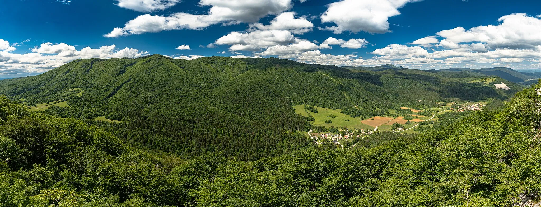 Photo showing: Črmošnjice valley (Črmošnjiška dolina) is a valley the Municipality of Semič in Bela krajina, southeastern Slovenia. The villlage in the middle is Srednja vas with the church of Saint Filip and Pavel. Above Srednja vas is the only ski slope in southeastern Slovenia called SC Gače. On the right is the village of Črmošnjice with the Parish Church of the Assumption of Mary. Photograph was taken from a viewing cliff below the hill of Markova glava (755 meters above sea level). The viewpoint is 758 meters above sealevel.