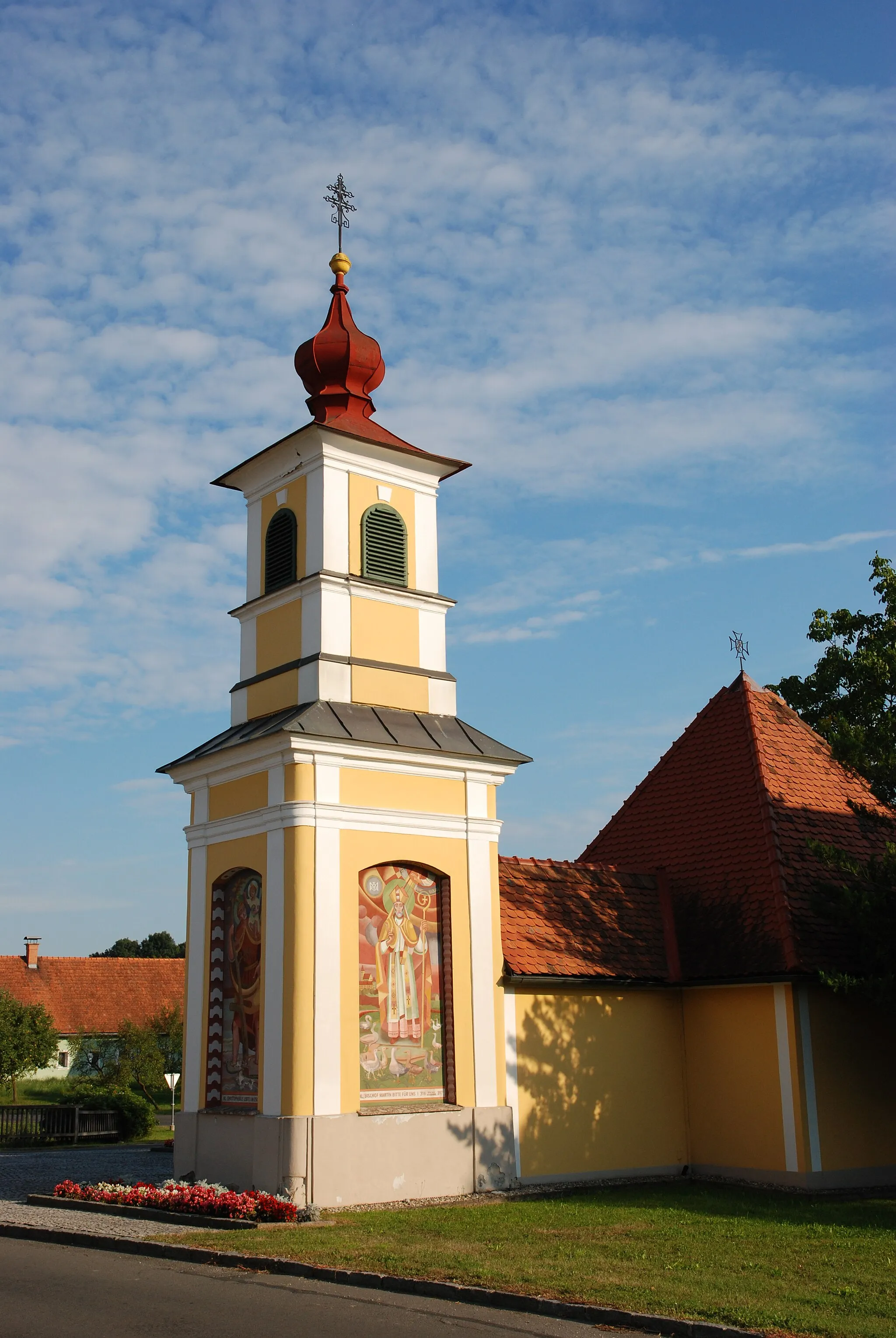 Photo showing: Ortskapelle Gosdorf.
Der Glockenturm wurde 1806 durch die Herrschaft von Brunnsee in barocken Formen erbaut. Der Kapellenzubau mit Kriegergedächtnisstätte stammt von Anton Walter und wurde 1968 geweiht. Aus demselben Jahr stammt der Altar mit einem Bild von Franz Weiss, von dem auch die Wandbilder am Turm stammen.