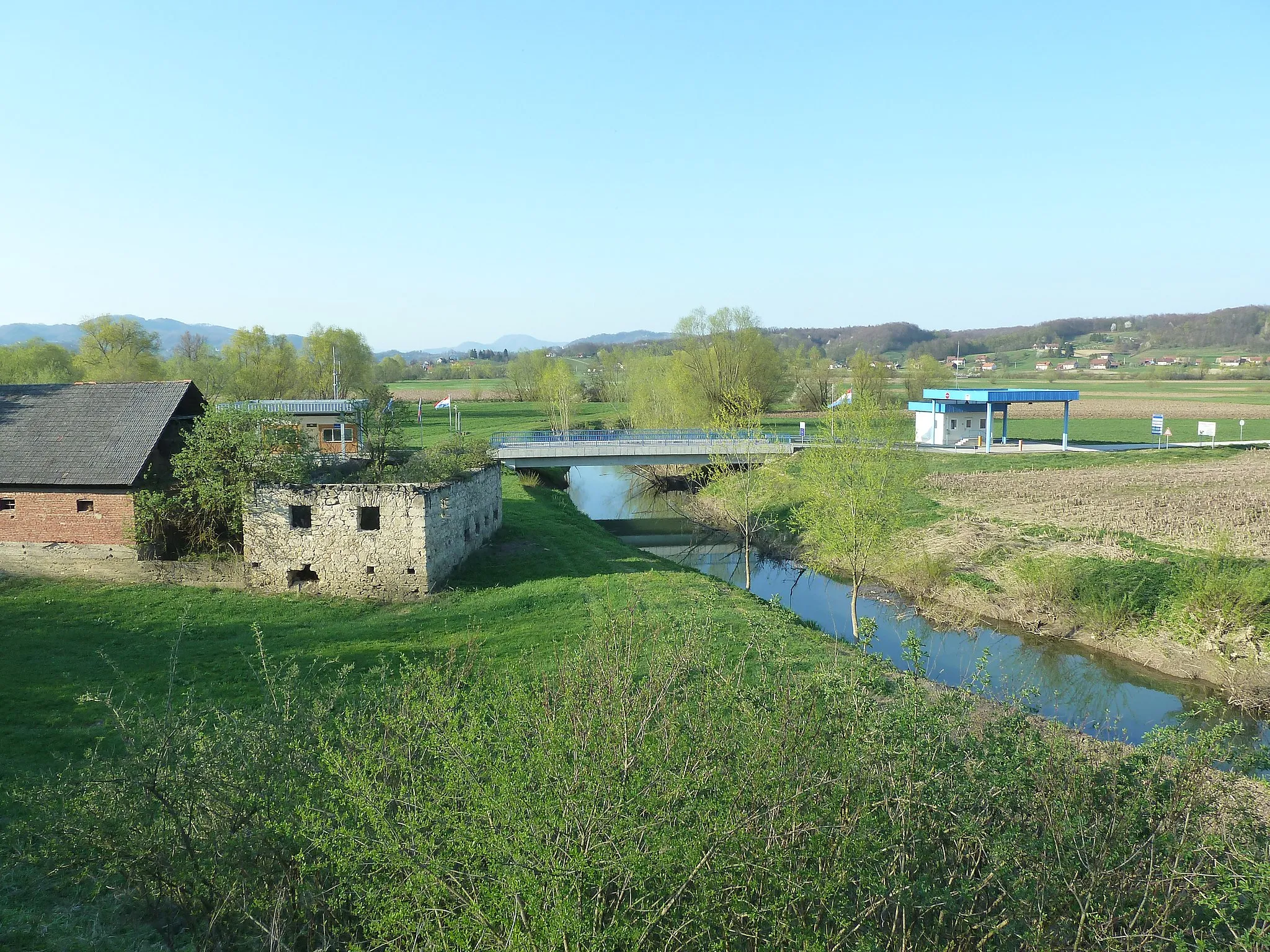 Photo showing: Sotla River at the village Sedlarjevo - an abandoned mill in the foreground, bridge and Slovenian and Croatian border crossing