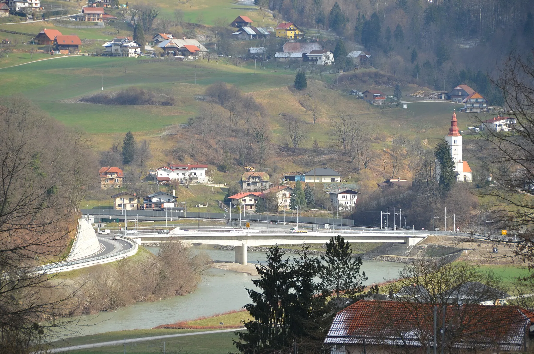 Photo showing: A 123 meter long bridge over Savinja River at Marija Gradec near Laško in Slovenia opened to traffic in 2021. The bridge spans the Savinja River with two asymmetric spans of 75 and 48 meters and one river support. On the photo, on right, is the church of Marija Gradec. The bridge was designed by Ponting Bridges, the client of the project was the Slovenian Infrastructure Agency (DRSI), the construction was carried out by Kolektor Koling.