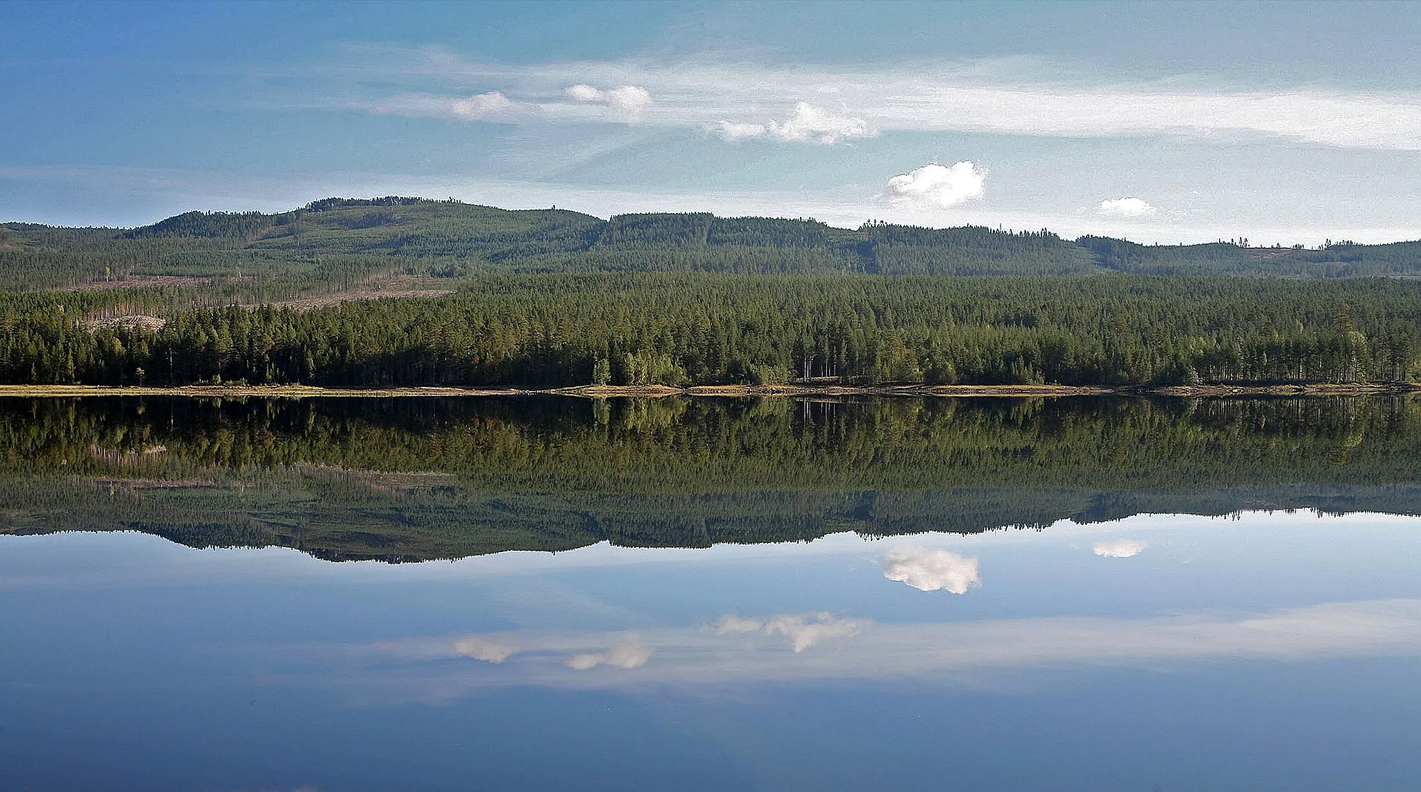 Photo showing: Reflection of the landscape in an absolutely still water surface of a reservoir near the town of Älvdalen in the province of Dalarna in Sweden.