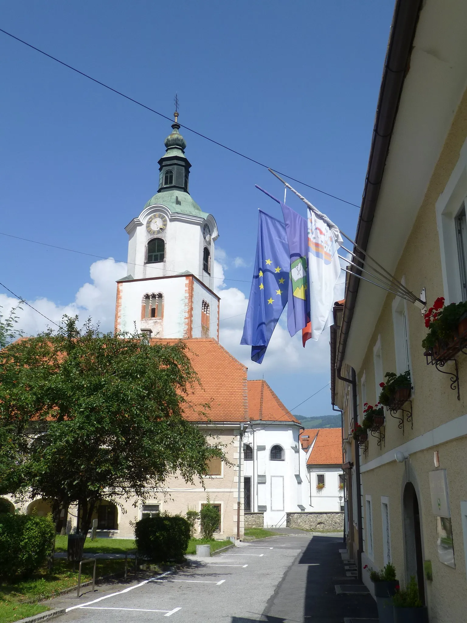 Photo showing: Tower of the Mary Church of Ruše. Probably the town-hall in shadow (flags). Slovenien Styria (Maria-Rast)