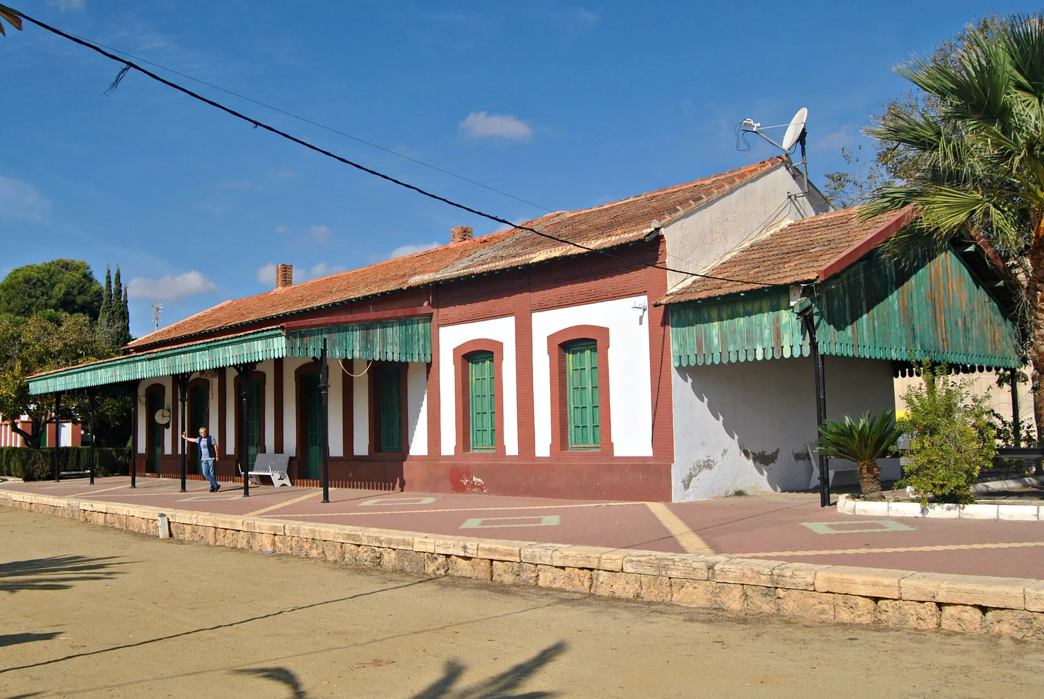 Photo showing: This image shows the restored station  at Zurgena (actually situated across the valley at La Alfoquia) Built in the 1890s principally to transport ore from the iron mines between Baza and Lorca to the port at Aguilas for export by ship. Only the Lorca to Aguilas section is still in use (mainly for passenger traffic, the mines being long closed). There are some remains of structures and civil engineering along the route of the line between Almendricos and Baza but the track was lifted by the end of the 1990s.  Zurgena was an important point on the railway as the weight of the iron ore freight meant that eastbound trains needed doubleheading and banking from here due to the steep gradient.