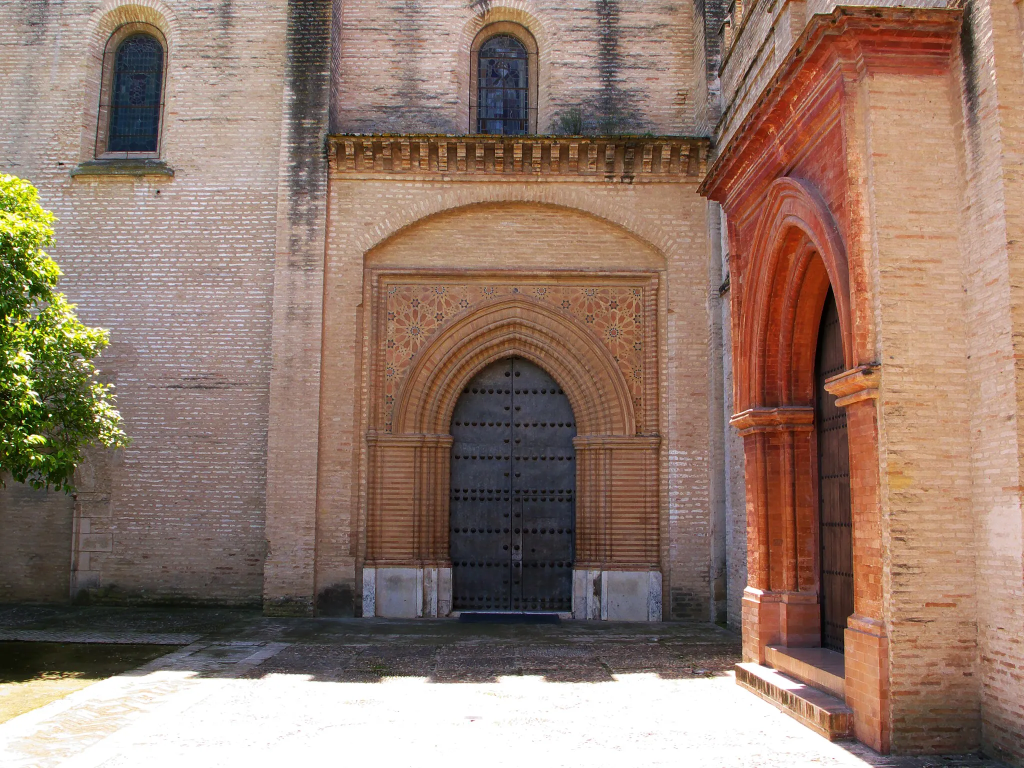 Photo showing: Portada norte (1350) de Diego Qui/xada y su /ermano. Fundado por Alfonso Pérez de Guzmán (1256-1309) como panteón real, concesión dada por Fernando IV (1298). En sendos sepulcros, los del fundador, su esposa María Alonso Coronel (†1330), su hijo Juan Alonso Pérez de Guzmán y Coronel (†1351) y su esposa Urraca Osorio de Lara, con epitafio, AQUI REPOSAN LAS ZENIZAS DE D. URRACA OSORIO DE LARA, MUGER DE D. JUAN ALONSO PEREZ DE GUZMAN, ILLMO. SEÑOR DE SANLUCAR, MURIO QUEMADA EN LA ALAMEDA DE SEVILLA POR ORDEN DEL REY DON PEDRO EL CRUEL, POR LE QUITAR LOS TESOROS E RIQUEZAS. TAMBIEN SE QUEMO CON ELLA PORQUE NO PELIGRASE SU HONESTIDAD LEONOR DAVALOS LEAL CRIADA SUIA. AÑO DE 1367