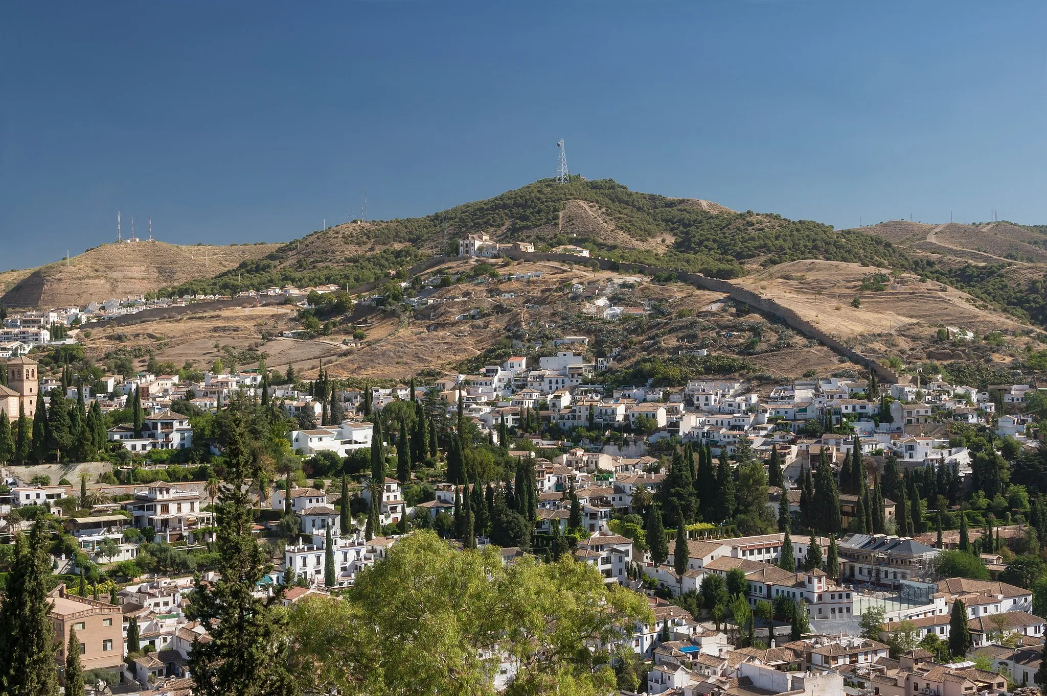 Photo showing: "Sacromonte" and arab nasrid city walls, seen from Alhambra. Notice the troglodyte inhabitations in the hill. Granada, Spain.
