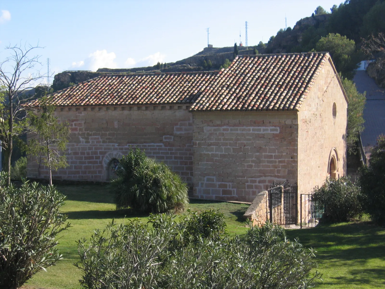 Photo showing: Se trata de una construcción que, partiendo de un núcleo original
románico del s.XII, sufrió diversas reformas y ampliaciones
entre los ss.XIV y XVI hasta alcanzar su aspecto actual,
caracterizado por algunos elementos típicos del llamado Gótico
del Bajo Aragón.
Tiene fábrica de sillar bien escuadrado. Consta de una nave
única con dos capillas laterales comunicadas entre sí en el lado
de la Epístola, a modo de pequeña nave lateral, y cabecera
recta. Asimismo se añadió otra capilla a los pies, de planta
cuadrada, que crea una cierta asimetría en la fachada de los
pies.
En dicha fachada occidental se abre una sencilla portada en
arco de medio punto dovelado sobre la que se observa un
óculo de iluminación.
Tanto el exterior como el interior destacan por su sobriedad.
En el interior llama la atención la decoración de las ménsulas
de las que parten los nervios que forman las bóvedas de crucería,
así como los motivos heráldicos de las claves de las
mismas que, por otro lado, aparecen decoradas con pintura

mural.