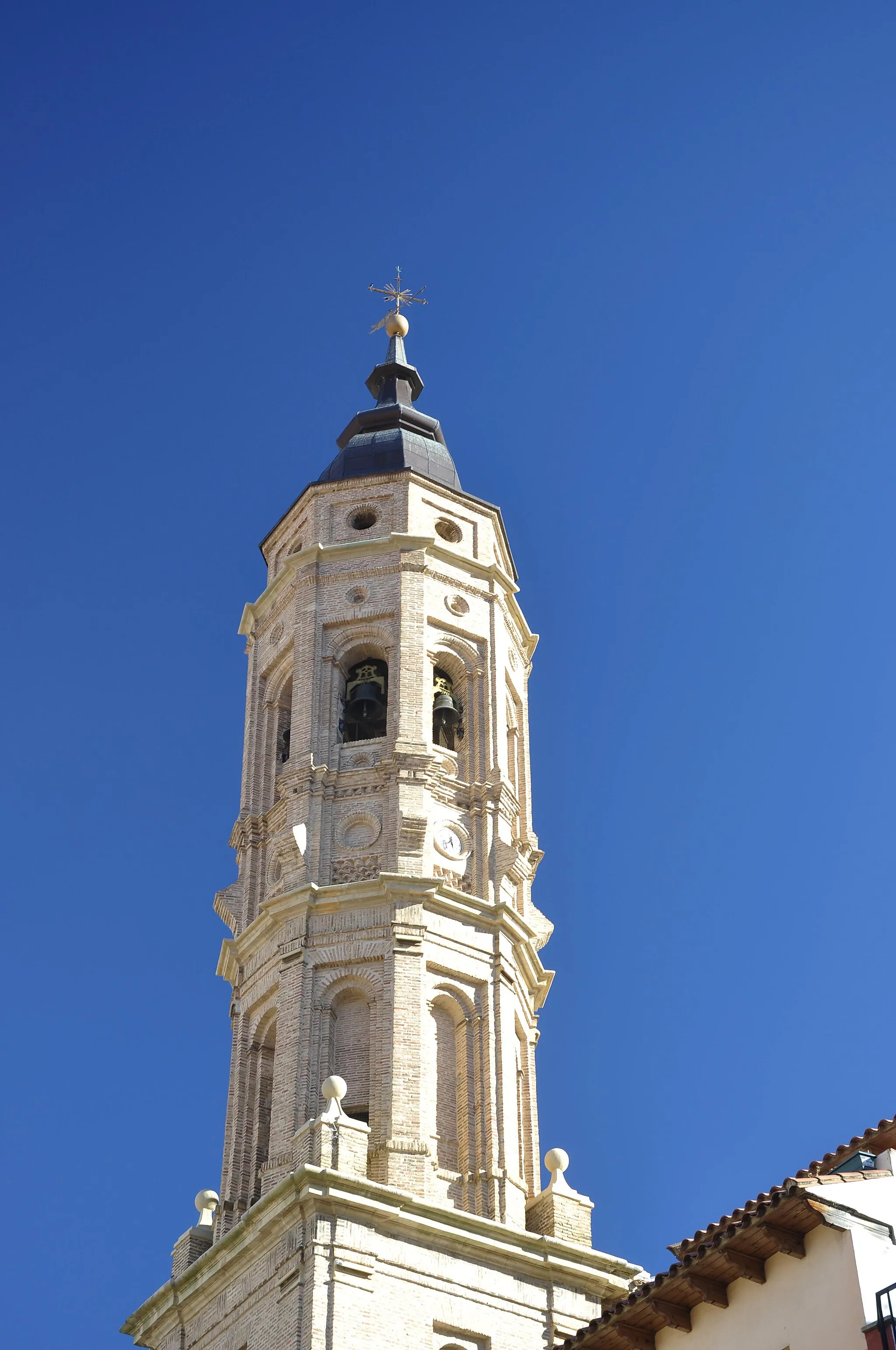 Photo showing: Se trata de un edificio de notables dimensiones articulado en
diferentes volúmenes. Destaca principalmente el volumen de
la nave central, flanqueada por las naves laterales, a las que
se adosan capillas en sus tres primeros tramos, creando un
marcado escalonamiento.
Las tres naves aparecen cubiertas con bóvedas de crucería
estrellada, mientras que las capillas presentan cubierta cupulada
rematada por linterna. El uso del estuco y la policromía
en tonos azules, amarillos y blancos en el interior hacen más
plástica la articulación de sus diferentes partes.
Por otro lado, la fábrica está realizada en sillar de piedra caliza
y al exterior sobresalen los potentes contrafuertes, la fachada
monumental y la esbelta torre de cuatro cuerpos ubicada en
su lateral izquierdo.
La fachada responde al modelo de fachada barroca compuesta
por dos cuerpos flanqueados por dos pares de columnas
salomónicas sobre plinto, separados por un entablamento y
coronados por un frontón curvo. En cada cuerpo se abre un
vano, correspondiendo el inferior poligonal a la portada y el
superior de medio punto a una hornacina.
La torre presenta estructura mixta, de planta cuadrada en su
dos cuerpos inferiores y octogonal en los dos superiores, realizados
éstos últimos en ladrillo siguiendo la tradición constructiva

mudéjar y rematados por un bulboso chapitel barroco.