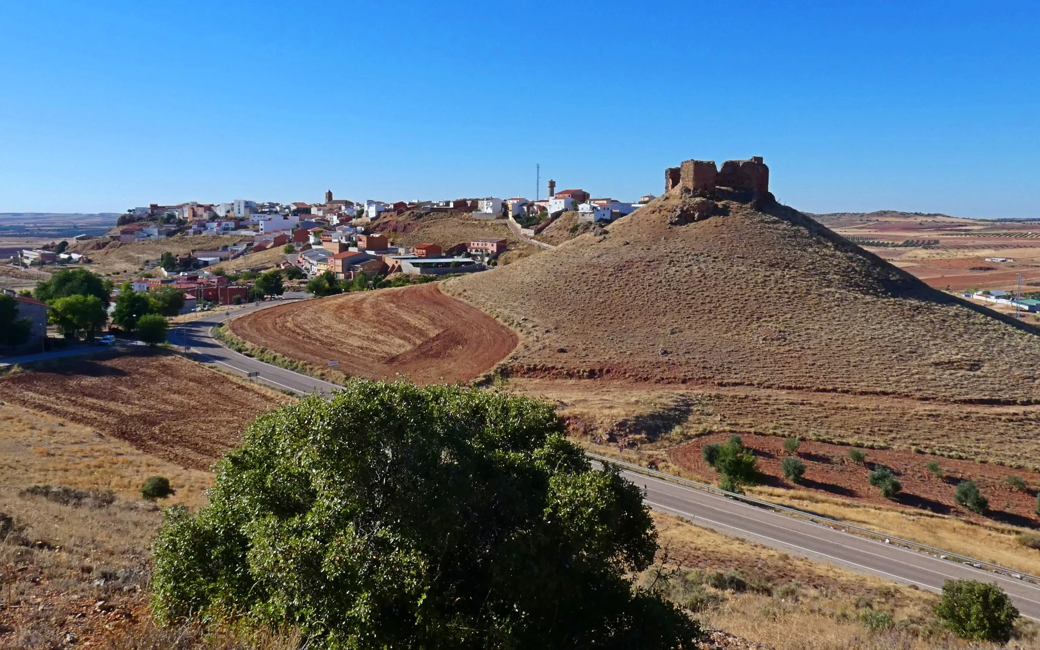 Photo showing: Este pequeño pueblo de Ciudad Real (1.009 habitantes) se llama así: Alhamrba, igual que el famoso palacio de La Alhambra de Granada. "alhamrah" en árabe significa "la roja". En esta población el nombre se lo dieron también los árabes cuando la ocuparon y se debe al color predominante de las tierras circundantes. El castillo original fue construido por los árabes sobre un cerro contiguo y se encuentra en ruinas.