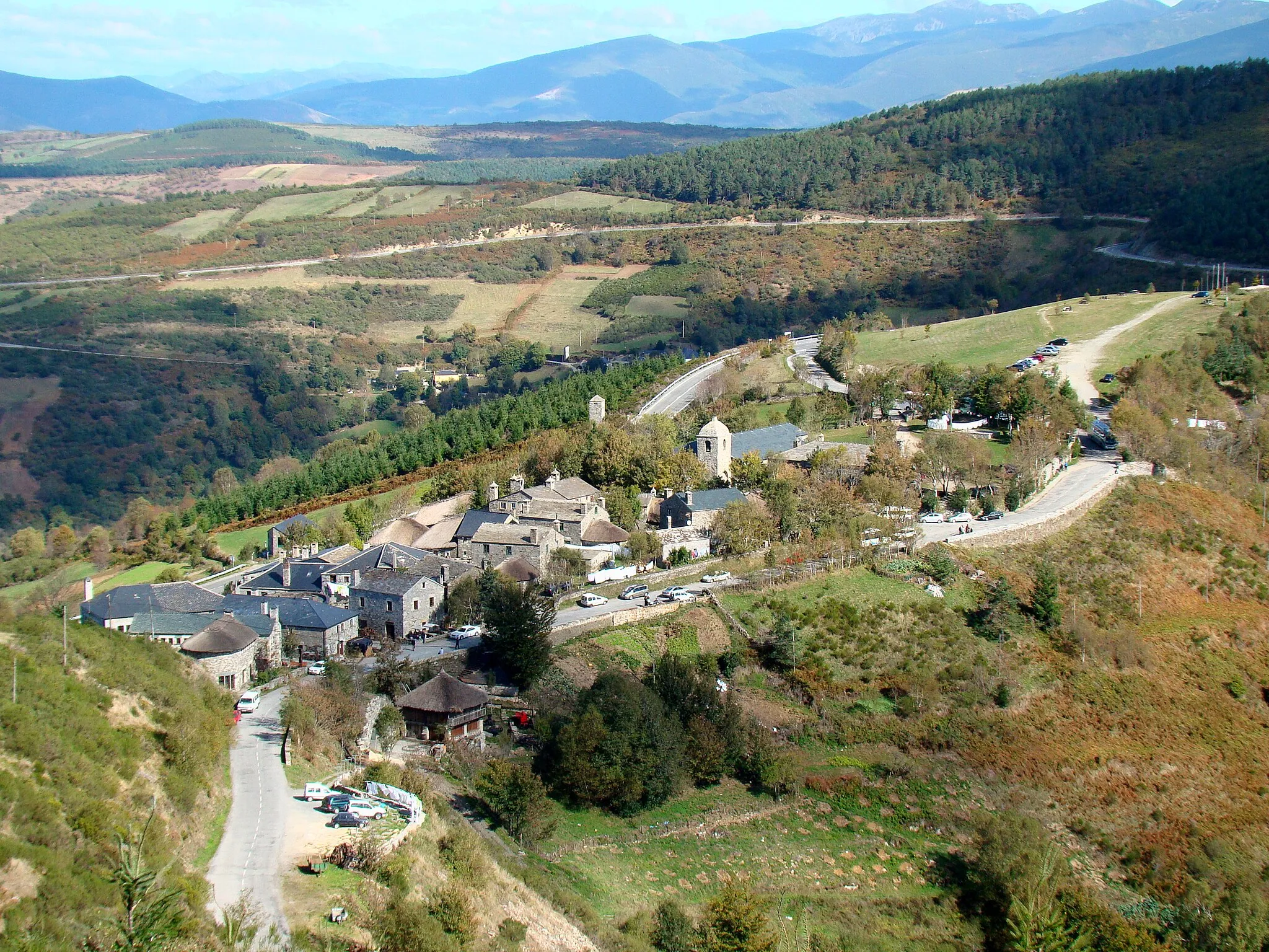 Photo showing: Pedrafita do Cebreiro as seen from a hill west of and above the village. The Way of Saint James enters the village near the bus leaving the parking lot in the upper right part of the photo, goes through the village and leaves it to the left near a pilgrims hostel.