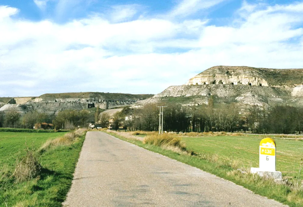 Photo showing: Route P-130 with milestone; on the slope, gypsum mines; in the background, the castle. Hornillos de Cerrato, Palencia, Castile and León, Spain