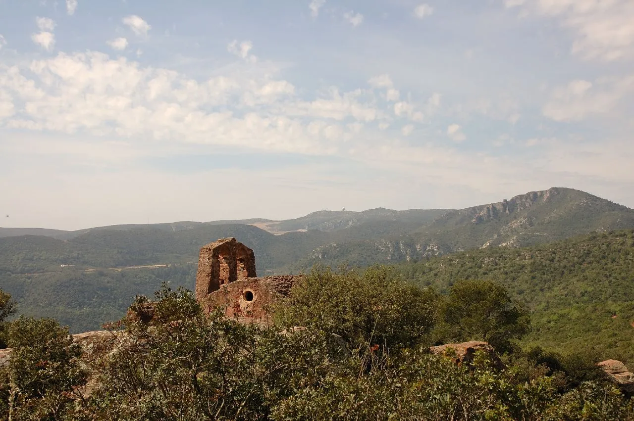 Photo showing: L'ermita del castell d'Eramprunyà. Al fons el massís del Garraf, la Morella i l'abocador de Barcelona que hi treu el nas