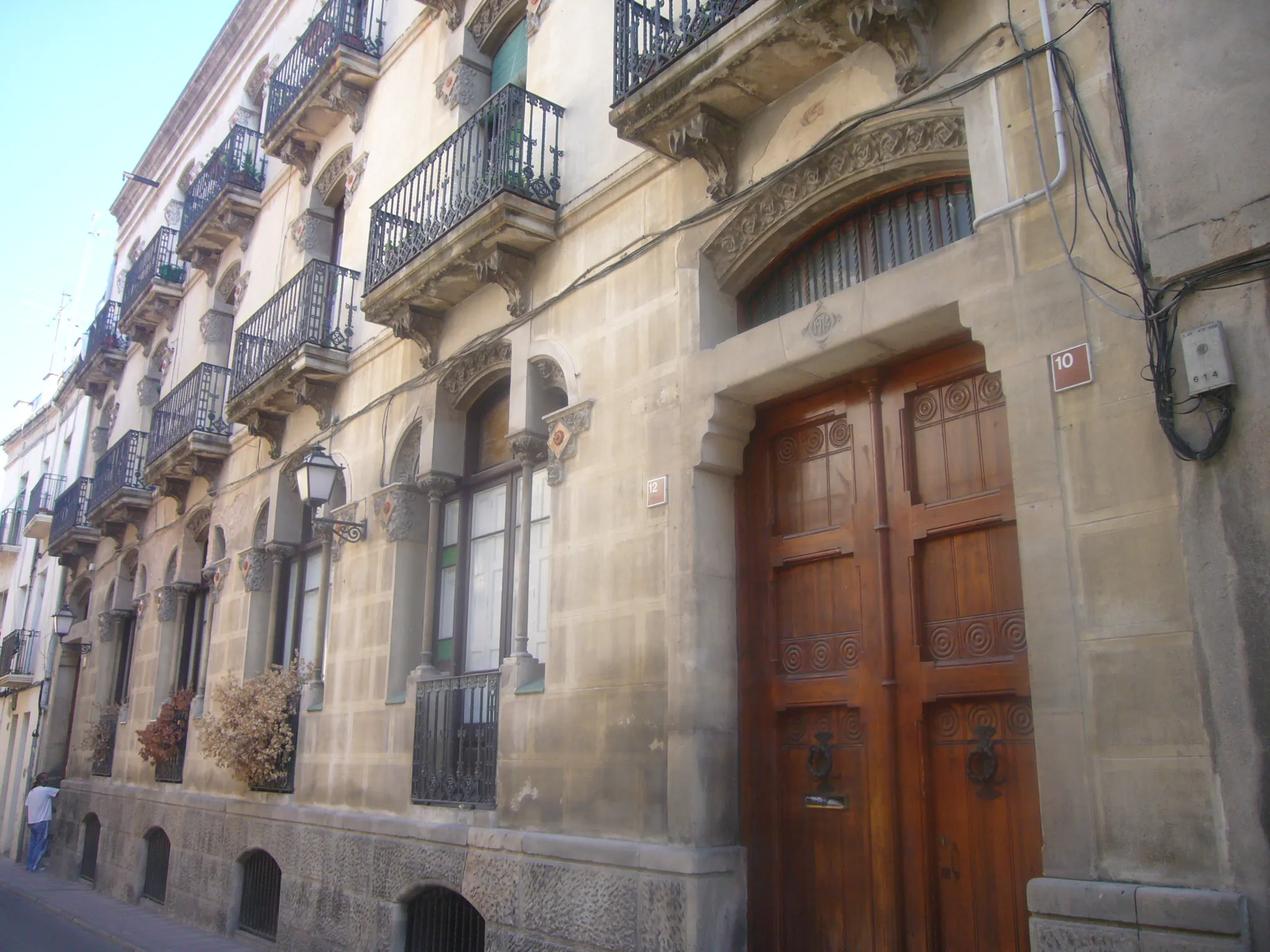 Photo showing: Casa Ramon Vives, també anomenada Cal Monets, edifici modernista d'habitatges de l'any 1913, situat al carrer Sant Roc, 10-14, d'Igualada, obra de l'arquitecte Josep Pausas i Coll. Promogut per l'adober Ramon Vives Maixenchs. Té una gran façana amb originals obertures. Les de la planta baixa són finestres balconeres amb llinda de tres lòbuls, partides en 3 trams per fines columnes. Té ornamentació amb relleus florals i aplics ceràmics.