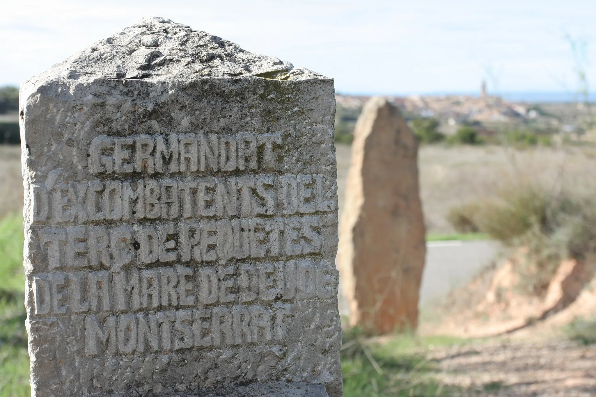 Photo showing: one of the Via Crucis stones, commemorating fallen Tercio de Nuestra Señora de Montserrat soldiers, at the so-called Cuatro Caminos battleground; the Vilaba dels Arcs town in the background