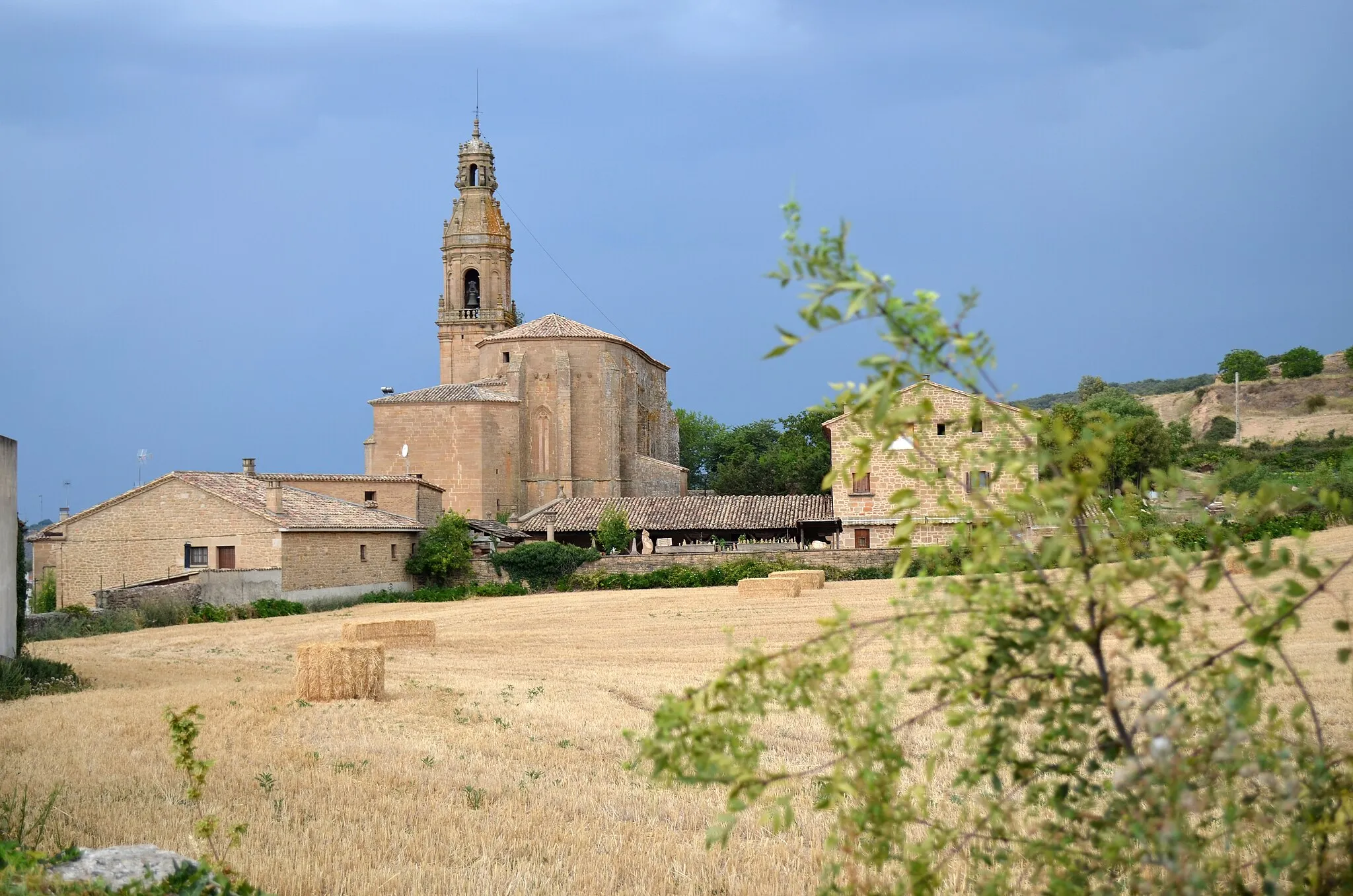 Photo showing: Vista del cabecero y la torre de la Iglesia de San Román, de Arellano (Navarra), desde el este; con un campo y vegetación en primer plano
