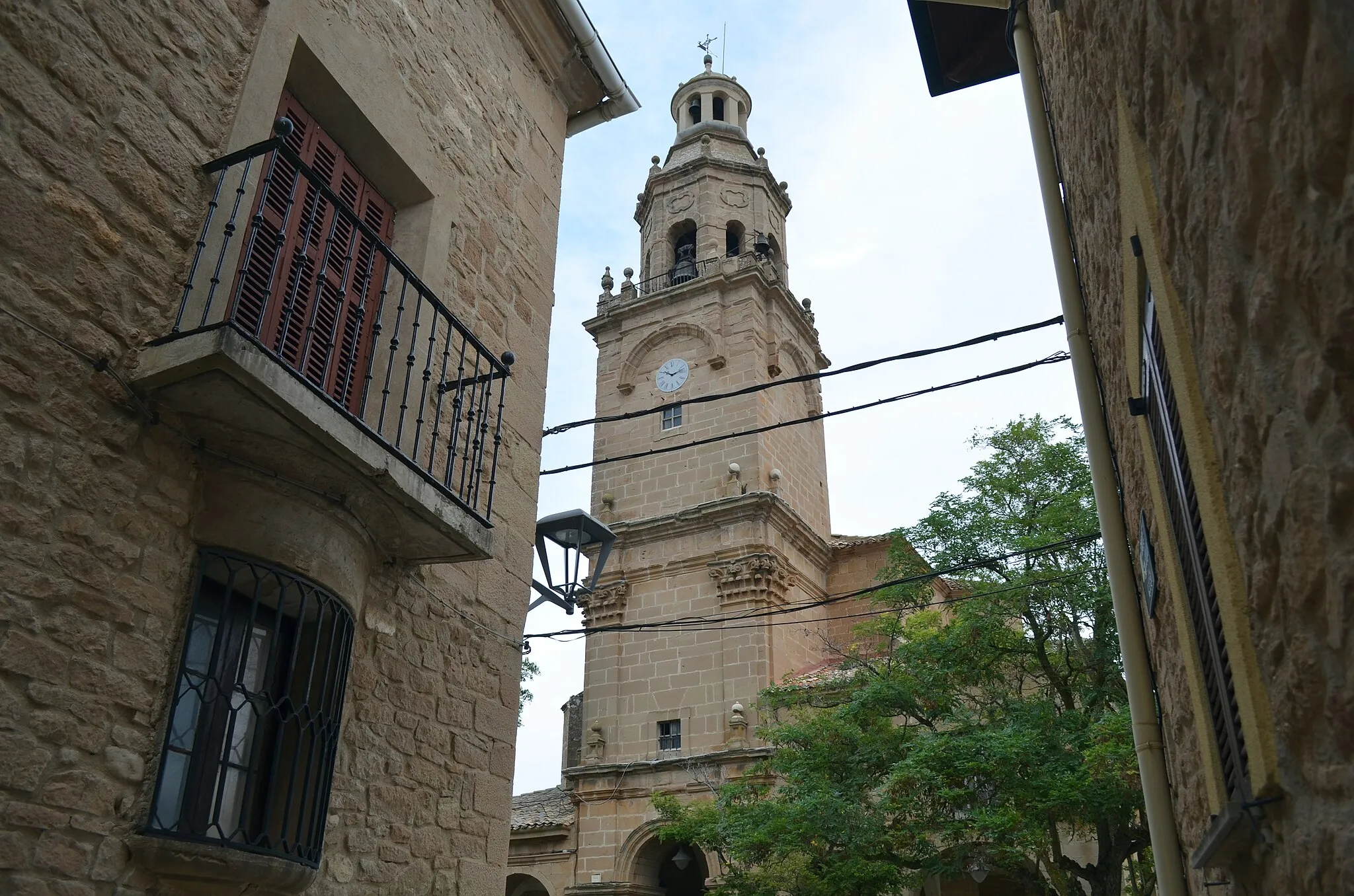 Photo showing: Vista de la torre de la Iglesia de San Cemeterio y San Celedonio, entre dos casas del pueblo con una ventana y balcón
