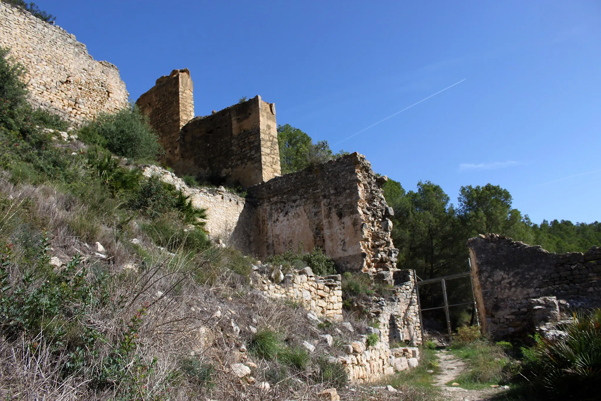 Photo showing: Castillo de Xivert. Muralla de la medina andalusí. Tras la toma de la fortaleza en el siglo XIII la población de su interior tuvo que trasladarse a la ladera norte para permitir la ampliación de las murallas. Se observa en la imagen parte de las construcciones de la medina, concretamente un edificio de grandes dimensiones con una de sus muros junto a una de las calles y las murallas que la rodeaban. Alcalá de Xivert, provincia de Castellón, Comunidad Valenciana, España.