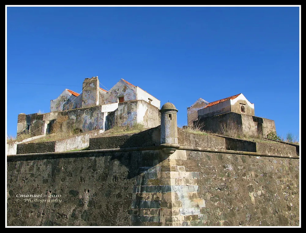 Photo showing: Caros amigos,
As fotos de hoje referem-se a  uma curta visita ao Forte de Nossa Senhora da Graça, também conhecido por Forte Lippe – actualmente em ruinas -, que visitei, pela primeira vez, em Novembro do ano passado.
Para além da sua primordial importância, nos Séc. XVII a XIX, na defesa de Elvas, e quiçá da nacionalidade, ele serviu durante vários anos de presídio militar, e nessa função está associado ao sofrimento de muitos militares, dos três ramos das Forças Armadas, que por via da sua conduta nele cumpriram penas.
Prestem atenção a algumas das fotos, que publicarei nas quais se vislumbra, bem, a pequenez das células onde os presos eram encacerados. 
Além disso, como no forte não havia nenhuma fonte, a água consumida era proveniente de cisternas, alimentadas pelas águas pluviais, e por barris de água que os prisioneiros, como castigo, eram obrigados a transportar da Fonte do Marechal, existente na parte baixa da encosta, a cerca de 1 Km. 
Para os interessados, fica aqui o link da fonte e sua história e os links respeitante a uma informação histórica mais completa sobre o forte em causa.

Um bom resto de semana.

Um abraço
Celestino Manuel
www.aguas.ics.ul.pt/portalegre_fmarechal.html
Fonte do Marechal ou Mina do Forte Lippe

“http://pt.wikipedia.org/wiki/Forte_de_Nossa_Senhora_da_Gra%C3%A7a
Forte de Nossa Senhora da Graça
O Forte de Nossa Senhora da Graça, oficialmente denominado como Forte Conde de Lippe, no Alentejo, localiza-se a cerca de um quilômetro a norte de Elvas, em Portugal.
Em posição dominante sobre o chamado Monte da Graça, integrava a defesa da Praça-forte de Elvas, que complementava.
História
No século XVII, a posição estratégica do monte da Graça, ocupada por tropas espanholas no contexto da Guerra da Restauração da independência, muito caro custou a Portugal durante o cerco a Elvas (1658-1659).
Um século mais tarde, durante a Guerra dos Sete Anos (1756-1763), a cidade sofreu novo sítio (1762). Com esse fato em mente, sob o reinado de D. José I (1750-1777), tendo o Marquês de Pombal chamado o Marechal Wilhelm von Schaumburg-Lippe, conde de Lippe para reorganizar o Exército português, determinou-lhe traçar planos para a modernização daquela praça-forte.
Os trabalhos do Forte da Graça iniciaram-se em 1763, estendendo-se até ao reinado de Dna. Maria I (1777-1816), que a inaugurou em 1792, com o nome de Forte Conde de Lippe, militar que havia proposto a sua construção e que comandou o Exército português entre 1762 e 1764.
O forte resistiu às tropas espanholas durante a chamada Guerra das Laranjas (1801) e, mais tarde, no contexto da Guerra Peninsular, às tropas do general Nicolas Jean de Dieu Soult, que a bombardearam (1811), não chegando a tomá-la.
Características
A estrutura, de planta quadrangular com cento e cinqüenta metros de lado, é completada por baluartes pentagonais nos vértices. Quatro revelins cobrem as cortinas, a meio das quais de inserem o portão monumental (Porta do Dragão) e três poternas.....”