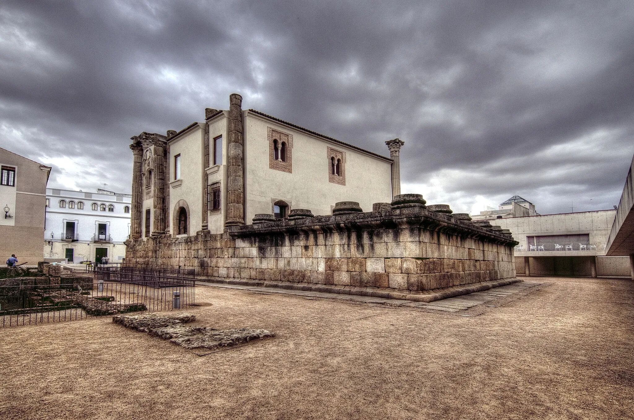 Photo showing: Templo de Diana es una construcción religiosa romana de finales del siglo I ubicada en Mérida (Extremadura, España). Mide unos 40 m de largo y 22 de anchura, es de planta rectangular y se rodea de columnas, de las cuales seis formaban el  pórtico y once cada lateral. Se cree que el templo estuvo dedicado al culto del Emperador Augusto, no a Diana, aunque este nombre se haya establecido tradicionalmente. En el siglo XVI se construyó el Palacio del Conde los Corbos adosado al templo y ocupando parte de su espacio interior. Es de estilo renacentista y se construyó aprovechando materiales romanos y visigodos. El palacio fue expropiado en 1972 y tras un inicio de derribo, fue conservado hasta el presente por considerarlo un elemento valioso aunque invada la cella del templo.