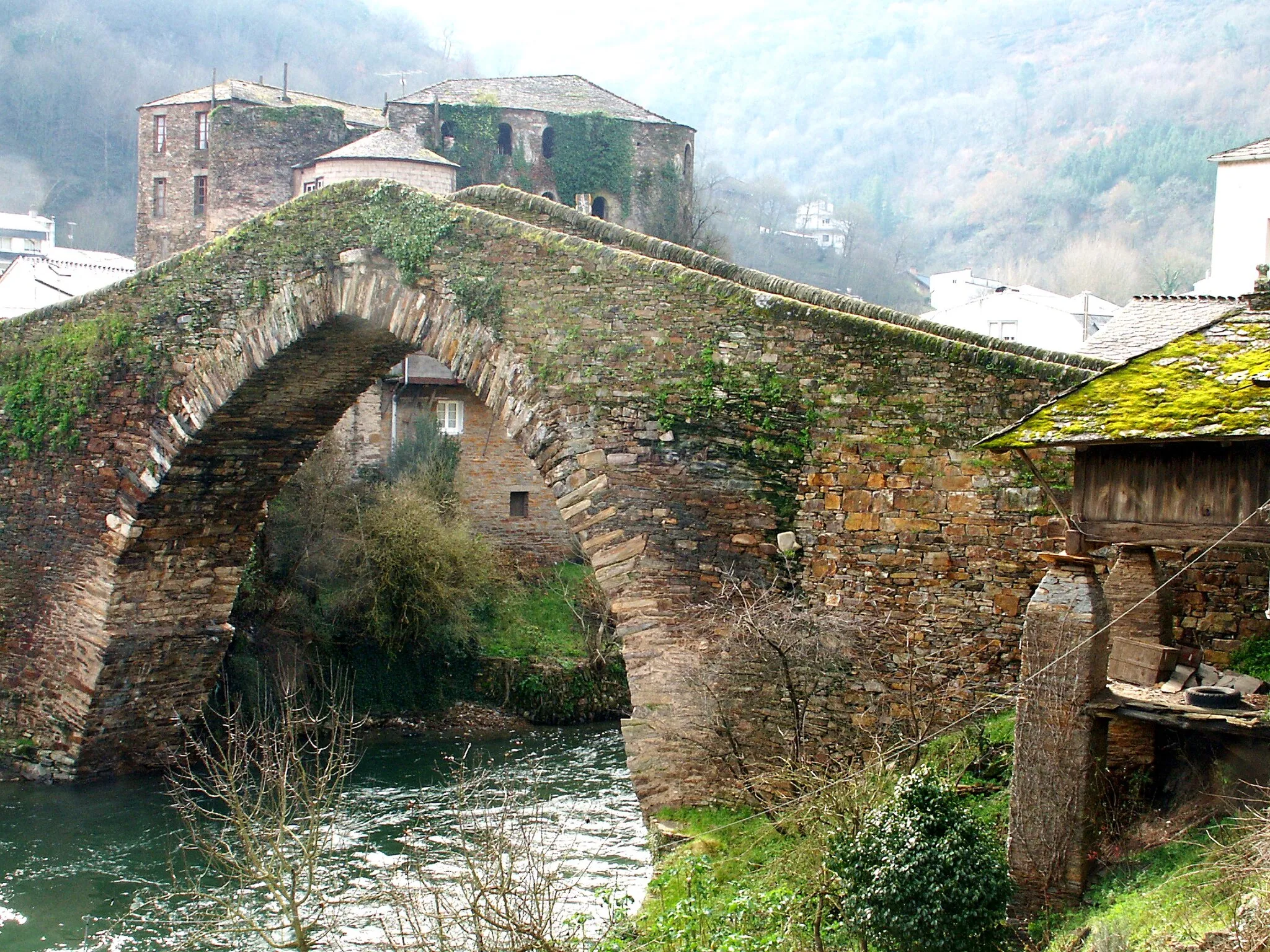 Photo showing: Navia de Suarna - Puente medieval sobre el rio Navia con el castillo de Navia al fondo