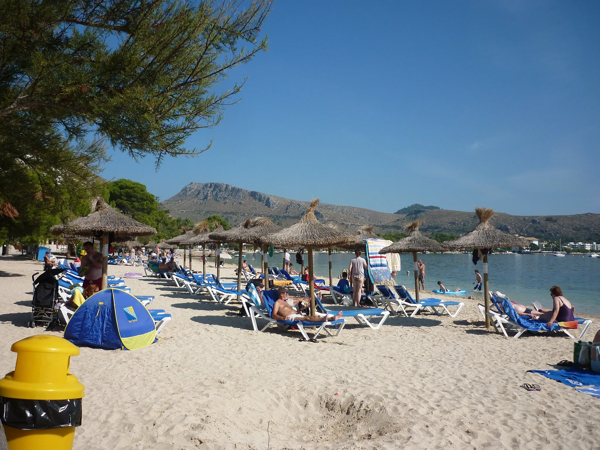 Photo showing: The small but lovely beach at Puerto de Pollenca. Get there early to bag some shade from the trees, otherwise hire an (expensive) parasol and lounger.