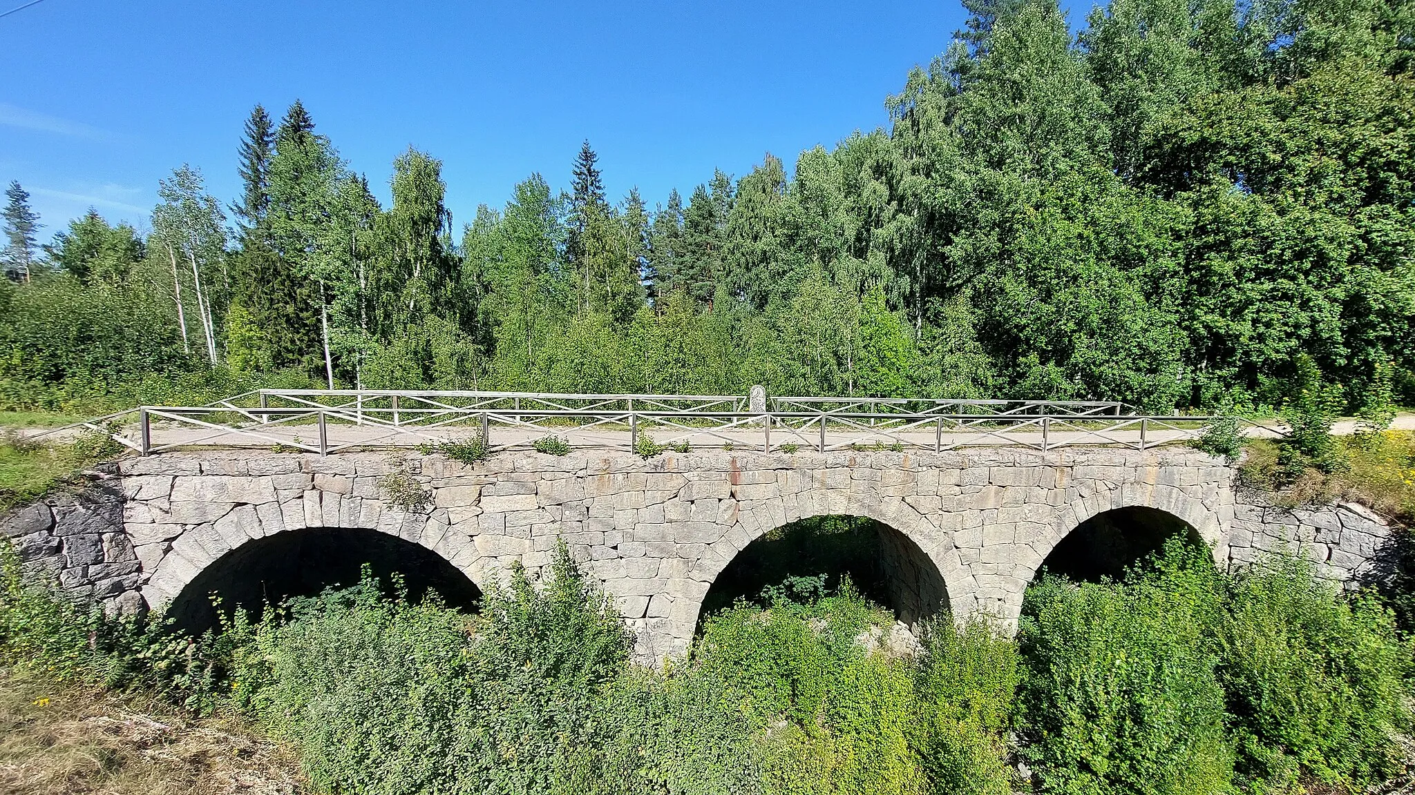 Photo showing: Gamla bron i Norränge i Bollnäs kommun i Gävleborgs län, fotad från den nya bron. I mitten av bron syns en minnessten.