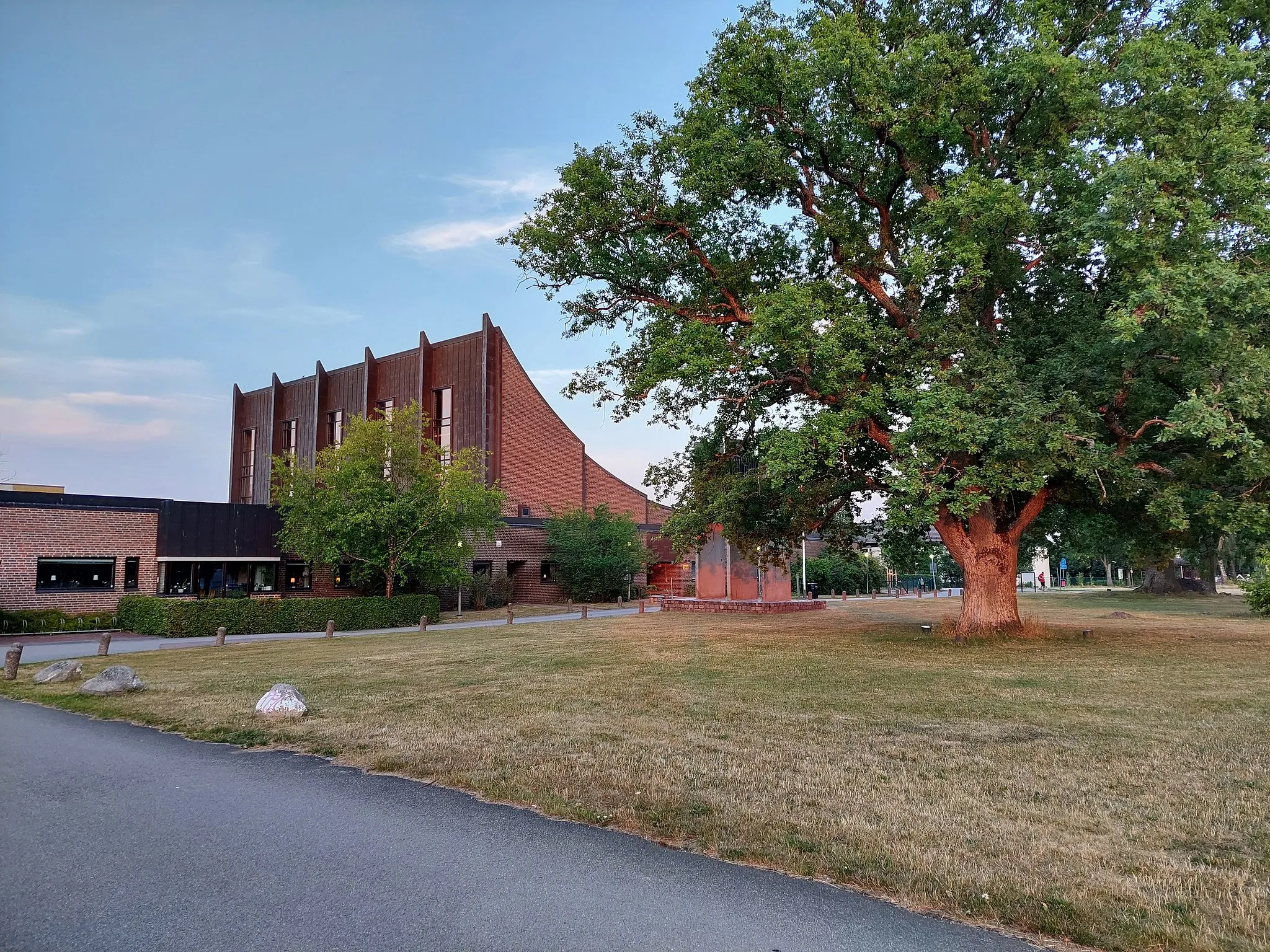 Photo showing: Skäggetorps kyrka i Linköping, sedd från nordväst, kvällen den 21 juli 2022. I förgrunden, till höger, syns en stor ek full med gröna blad.