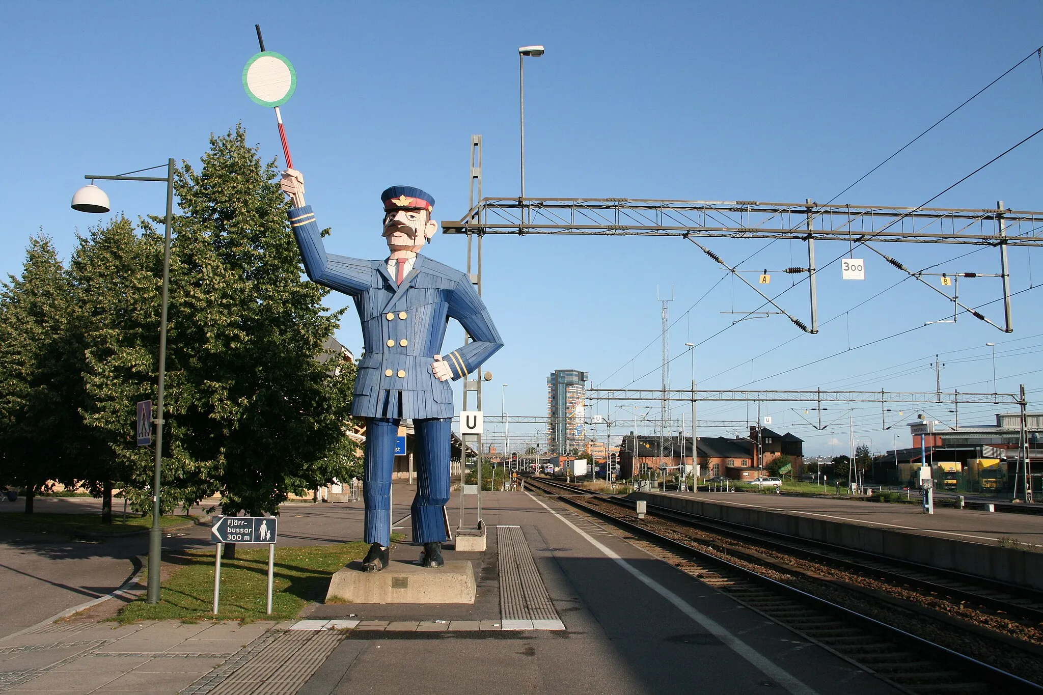 Photo showing: Wooden statue of a train station inspector, at Linköping central station in Linköping, Sweden. Such wooden sculptures were made by woodcraft teacher students around Linköping's 700th anniversary in 1987. One was donated to the sister city Palo Alto in California.