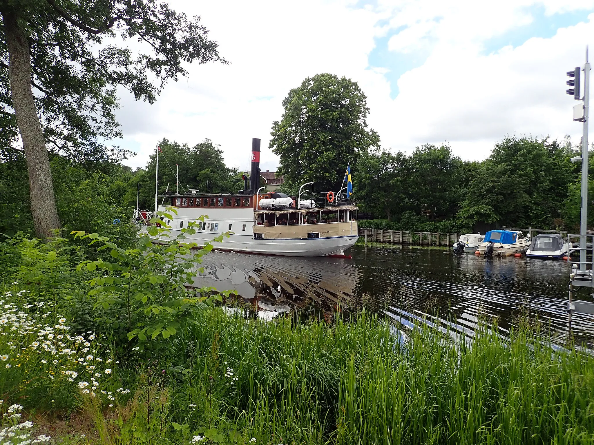 Photo showing: M/S Enköping from 1868 has just passed the Flottsund bridge in the Fyris river on her way from the centre of Uppsala to Mälaren on July 6, 2019. The picture is taken from the Kungshamn-Morga nature reserve.