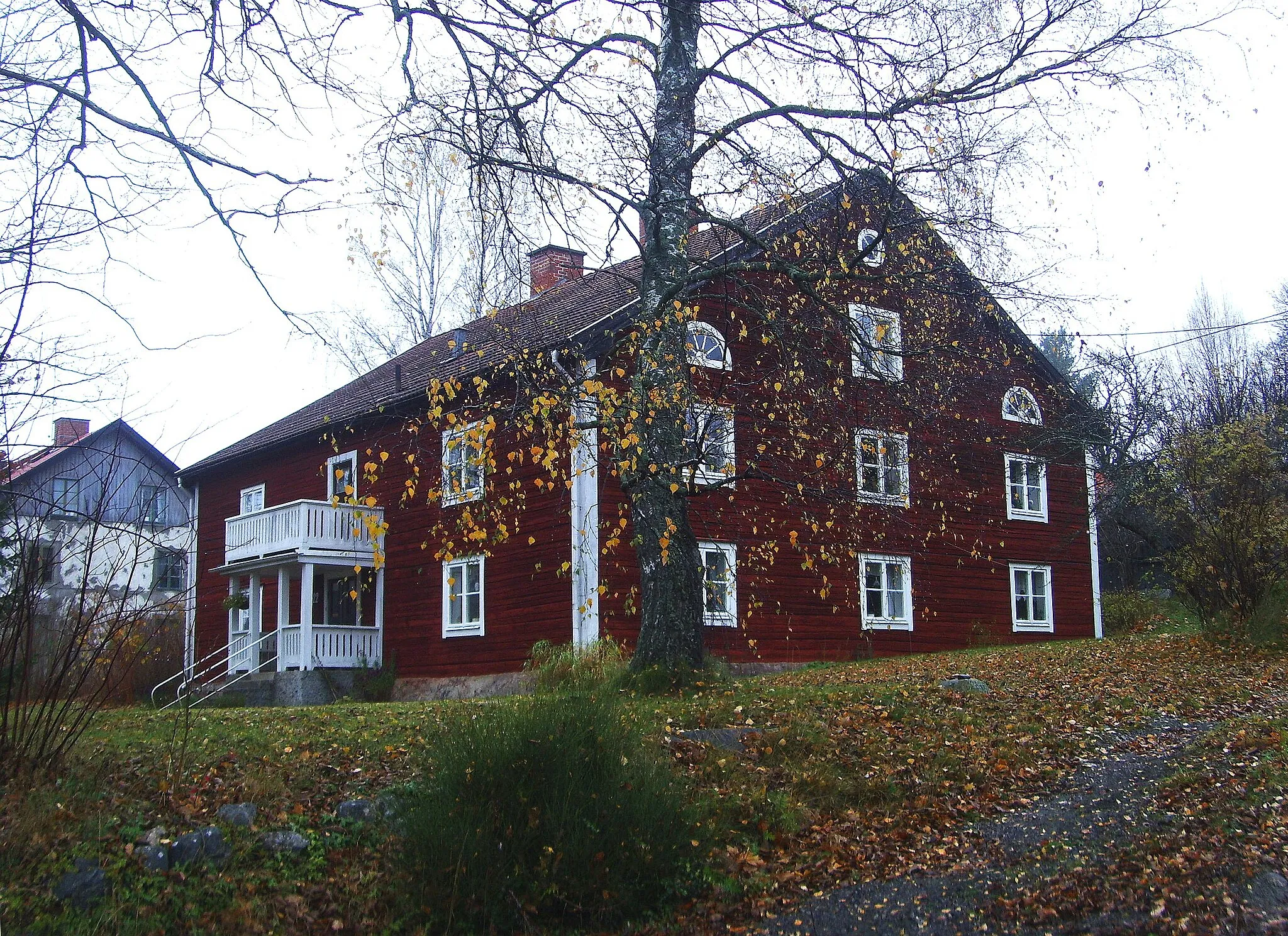Photo showing: Bostadshuset Bomarsund vid bruksgatan i Rejmyre byggdes år 1830. Huset är byggt på gråstensgrund av liggande timmer, rödmålat och med tegeltak. Nedre våning byggdes för en lägenhet med ett rum och kök samt fyra spisrum. Övre våningen hade samma rumsindelning. På vindsvåningen byggdes två spisrum. Namnet Bomarsund fick bostadshuset efter den ryska fästningen Bomarsund på Åland.