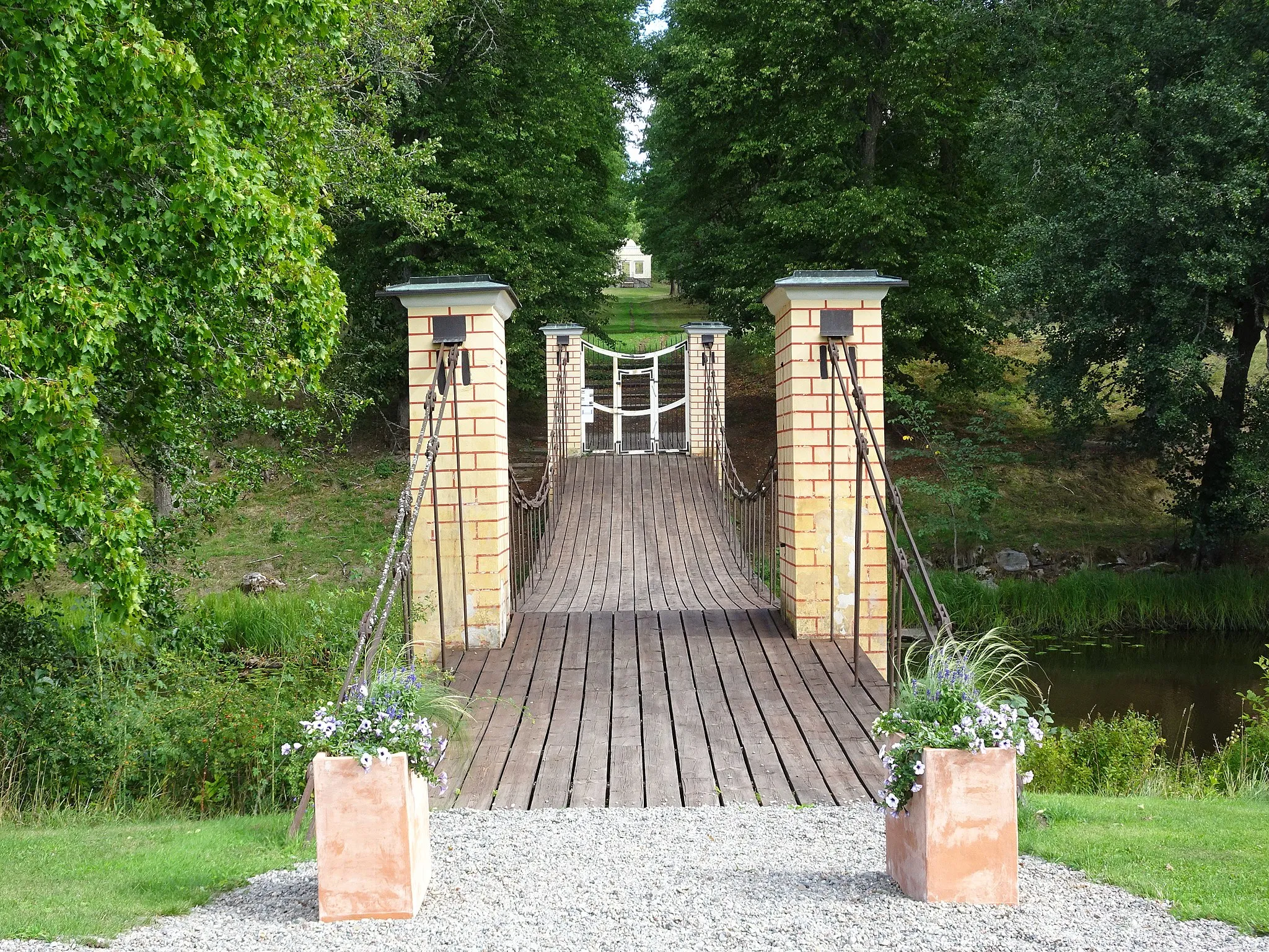 Photo showing: The mansion in Svanå, Sweden. The suspension bridge over Svartån leads to the english garden.
