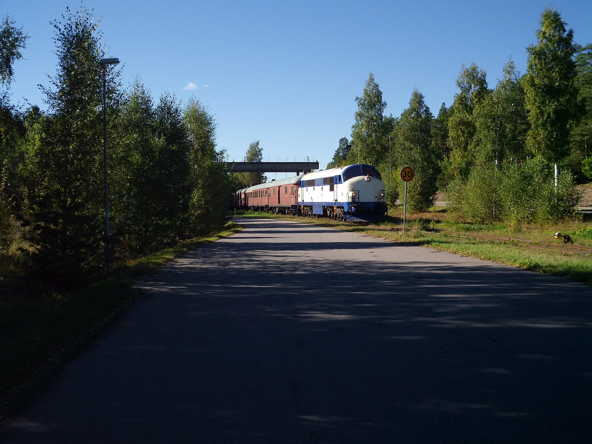 Photo showing: Tourist train passing under disused mining equipment, while returning from a business track towards Blomstermåla, Sweden.